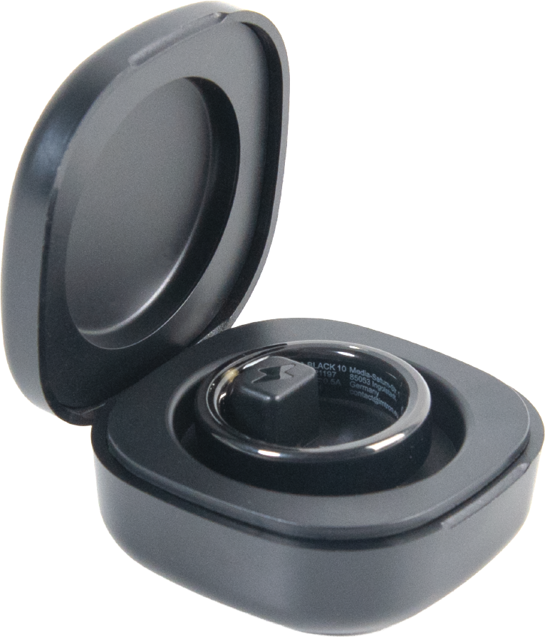 Une bague intelligente noire repose dans son boîtier de charge ouvert avec un petit plot de charge carré.