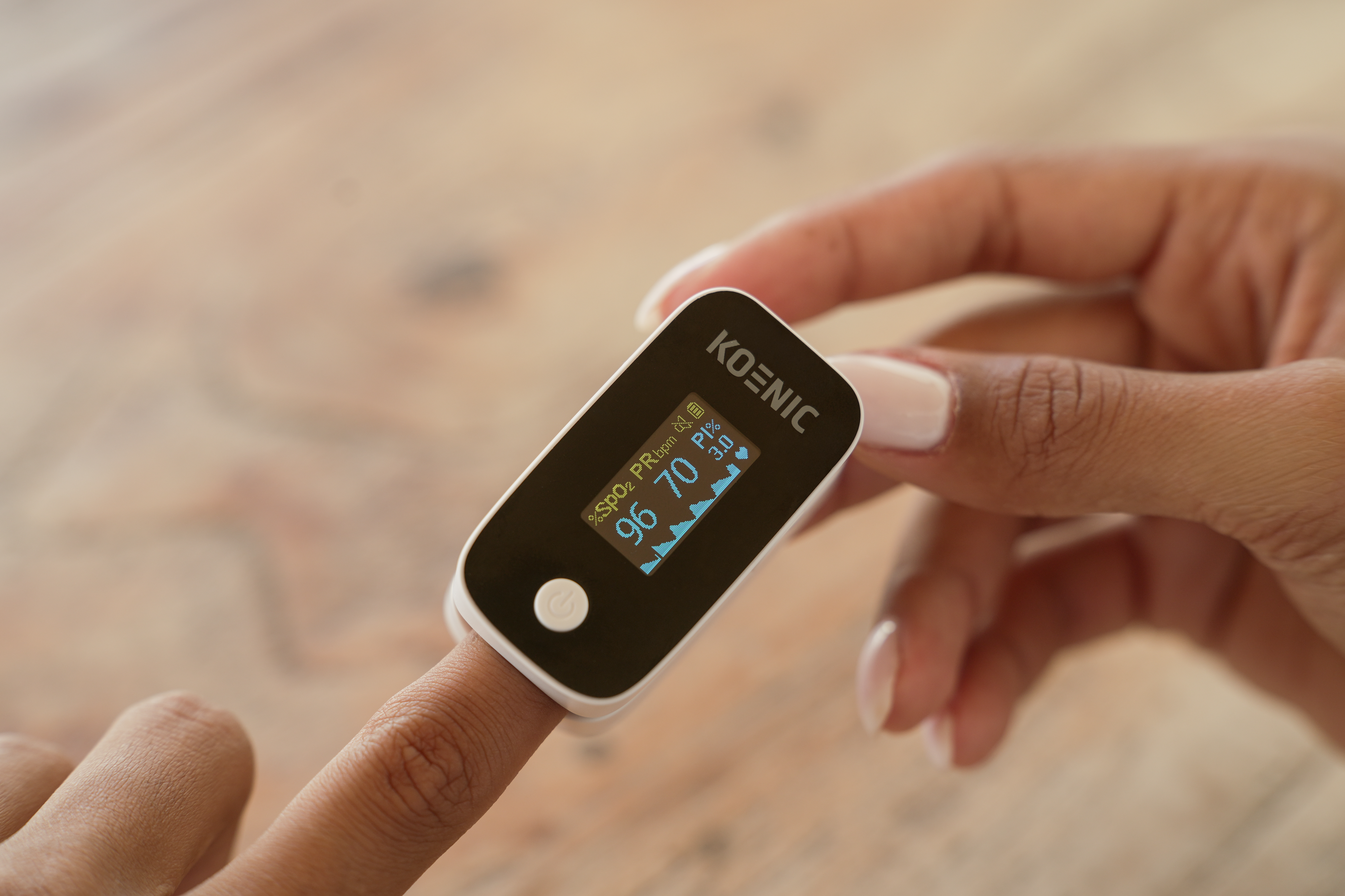 Finger pulsoximeter on a person's finger, showing oxygen saturation and pulse rate on a digital display.