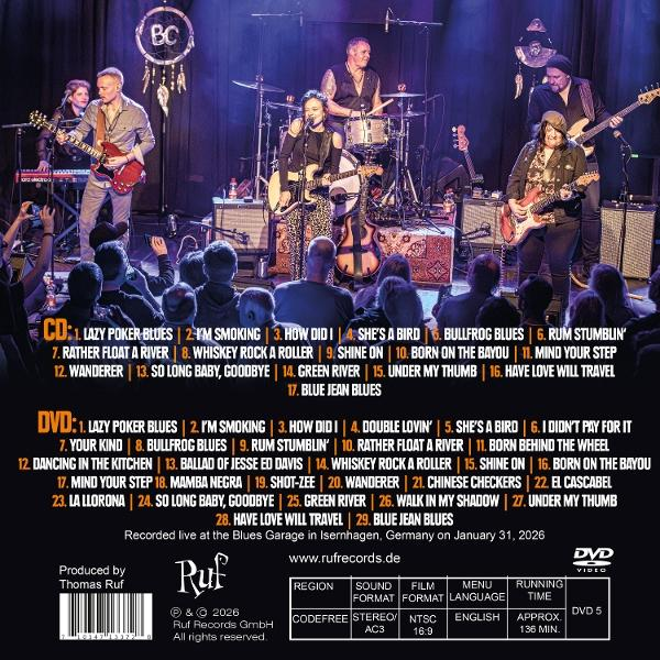 Live-Konzertband auf der Bühne mit CD- und DVD-Titelliste davor.