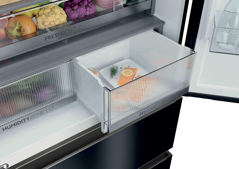 Offene Kühlschrank-Schublade MYZONE mit rohem Lachsfilet, Zitrone und Kräutern auf einem weißen Teller.