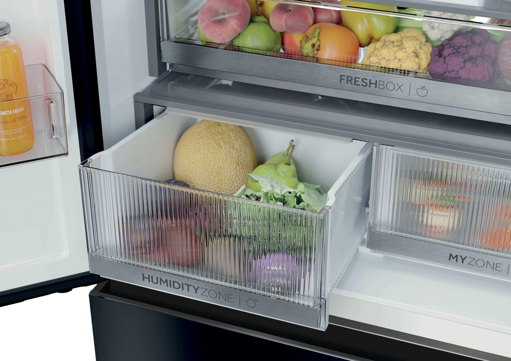 Ein offener Kühlschrank mit einer Humidity Zone Schublade gefüllt mit Melone, Birnen und Gemüse.
