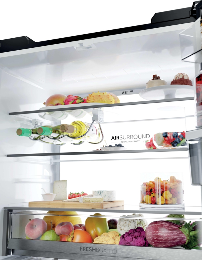 Innenansicht eines Kühlschranks mit frischem Obst, Gemüse, Weinflaschen, Käse und Gebäck.