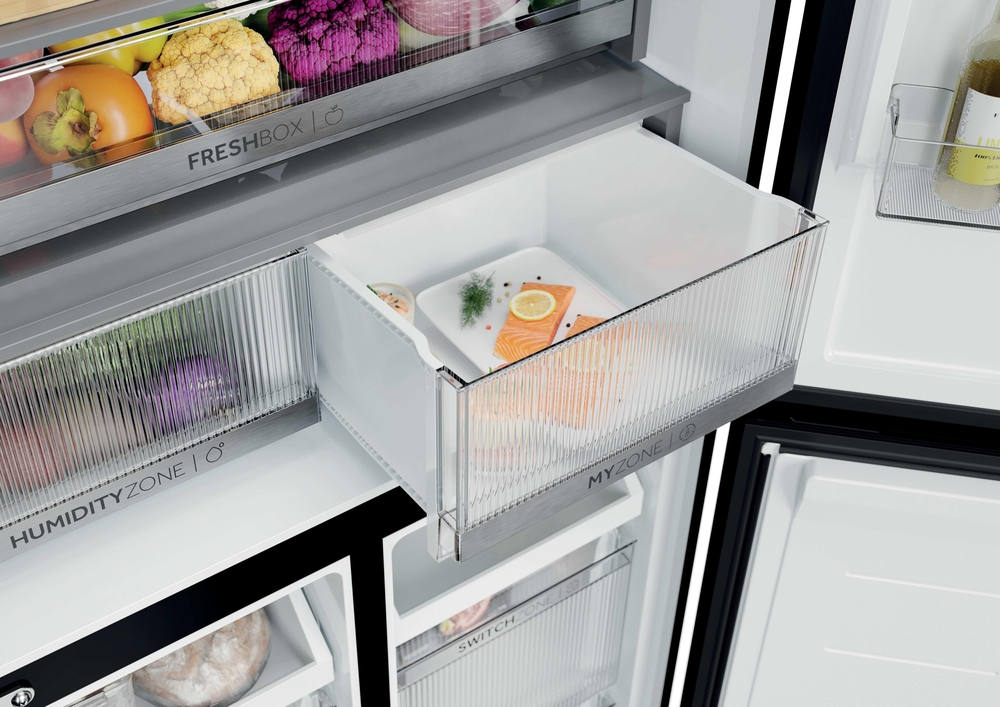 Offene Kühlschublade mit Lachsfilet, Zitrone und Kräutern, umgeben von weiteren Fächern mit Gemüse und Obst.