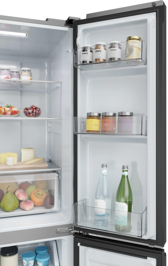 Offener Kühlschrank mit Gläsern, Flaschen, Obst und Käse auf den Regalen und in der Tür.
