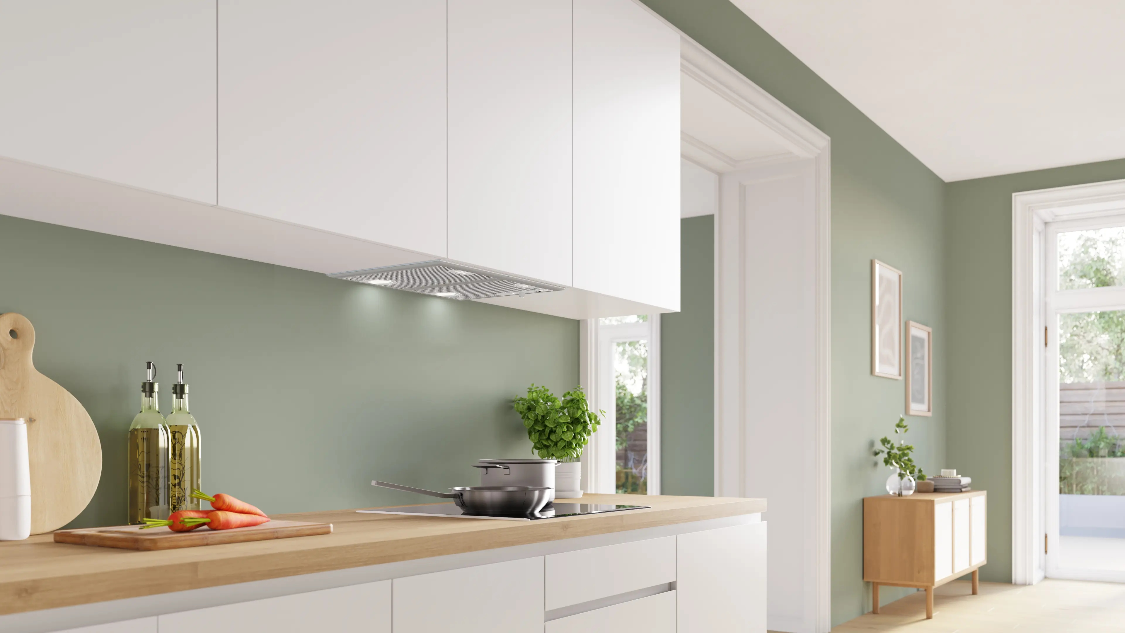 Moderna cocina verde con armario blanco, encimera de madera, zanahorias en una tabla y utensilios.
