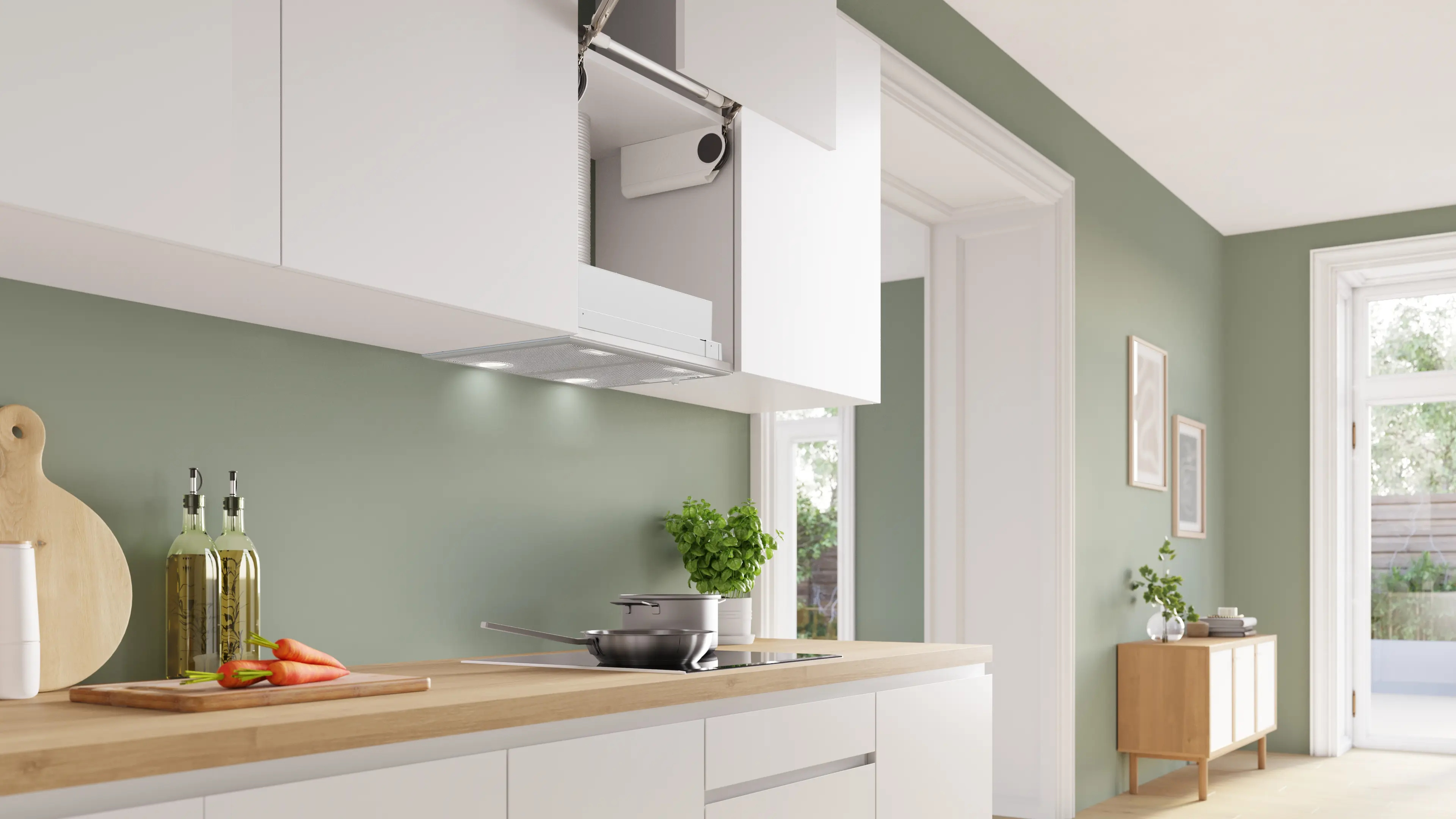 Cocina moderna con gabinetes blancos, pared verde y encimera de madera con botellas de aceite y zanahorias.
