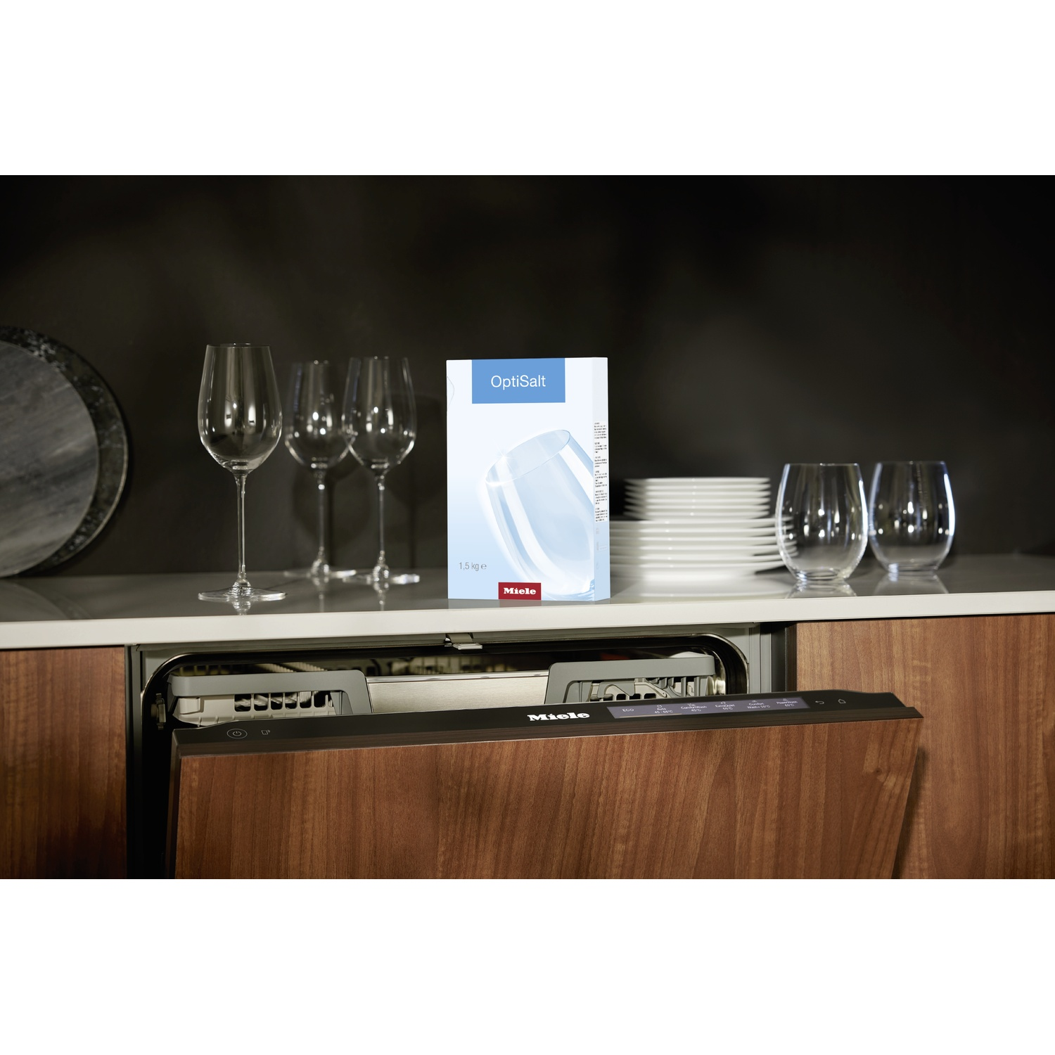 Lave-vaisselle avec façade en bois dans une cuisine. Des verres à vin, de la vaisselle et une boîte de Miele OptiSalt.