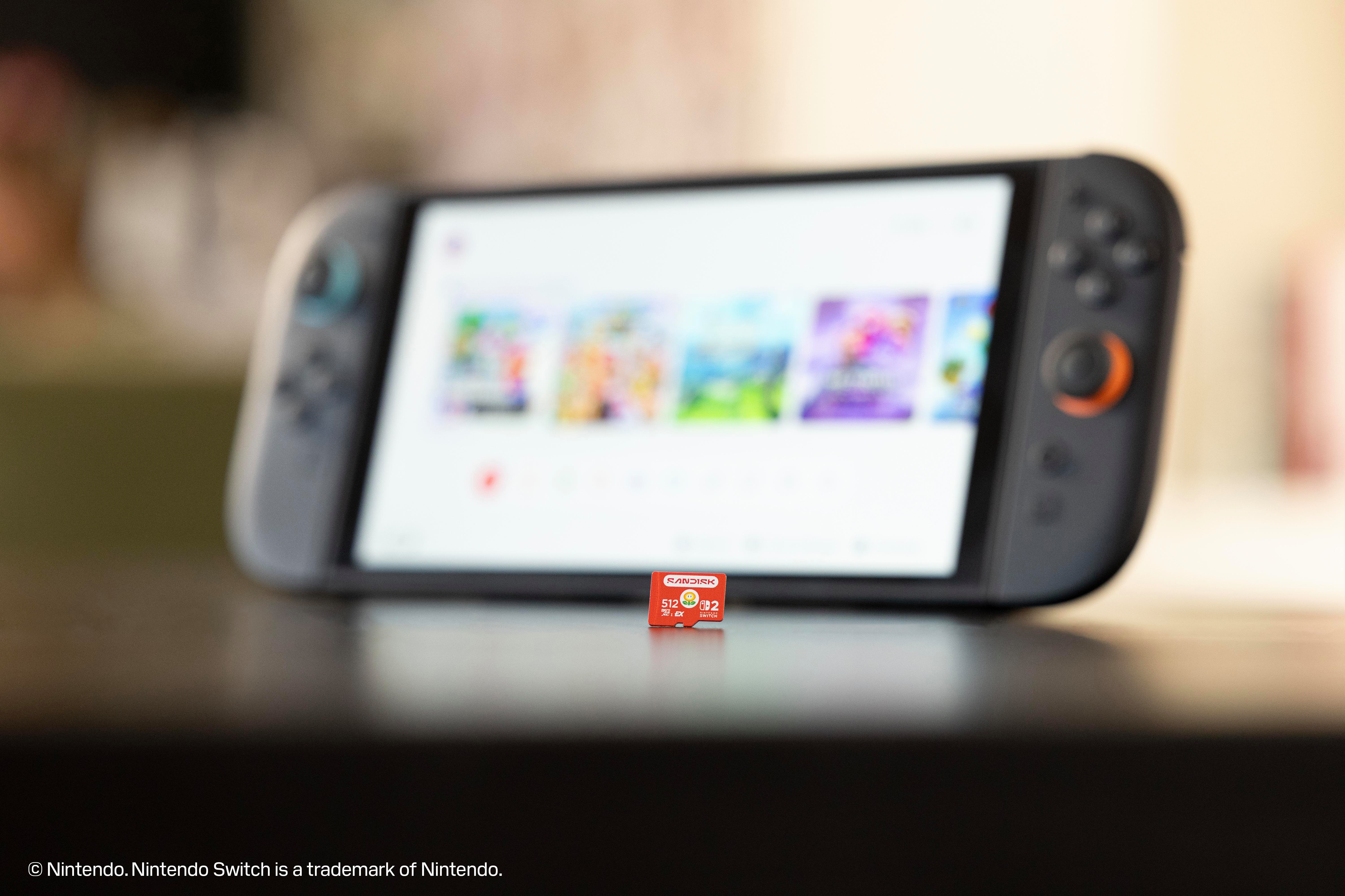 Eine rote SanDisk 512GB MicroSD-Karte für Nintendo Switch liegt auf einer dunklen Oberfläche vor einer unscharfen Konsole.