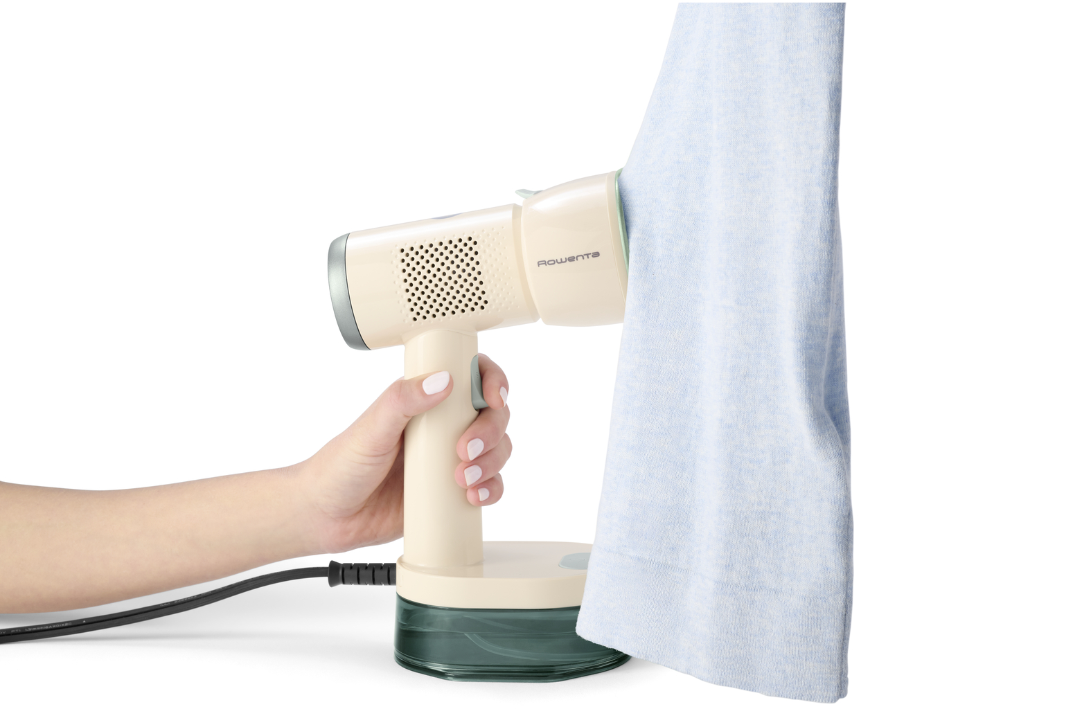 Una mano sostiene un vaporizador de ropa portátil de color crema, quitando arrugas de una prenda azul.