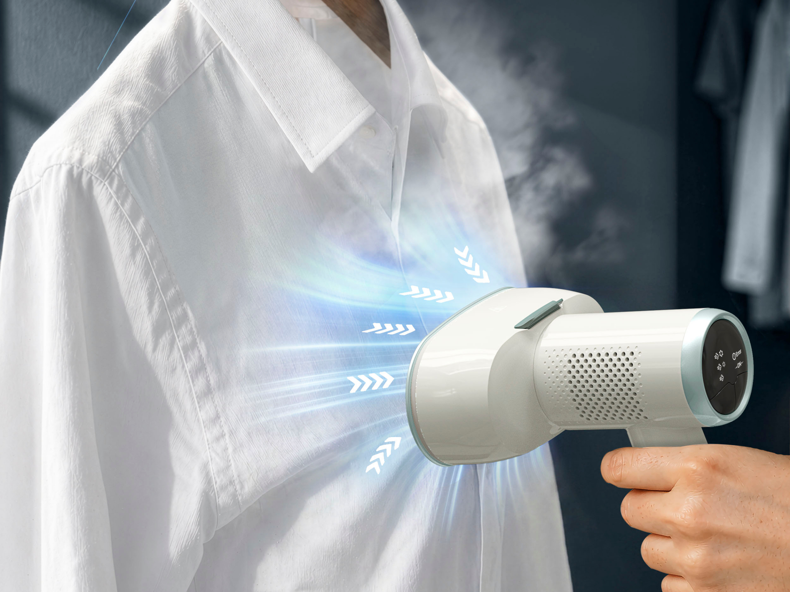 Un vaporizador de ropa de mano alisa una camisa blanca.