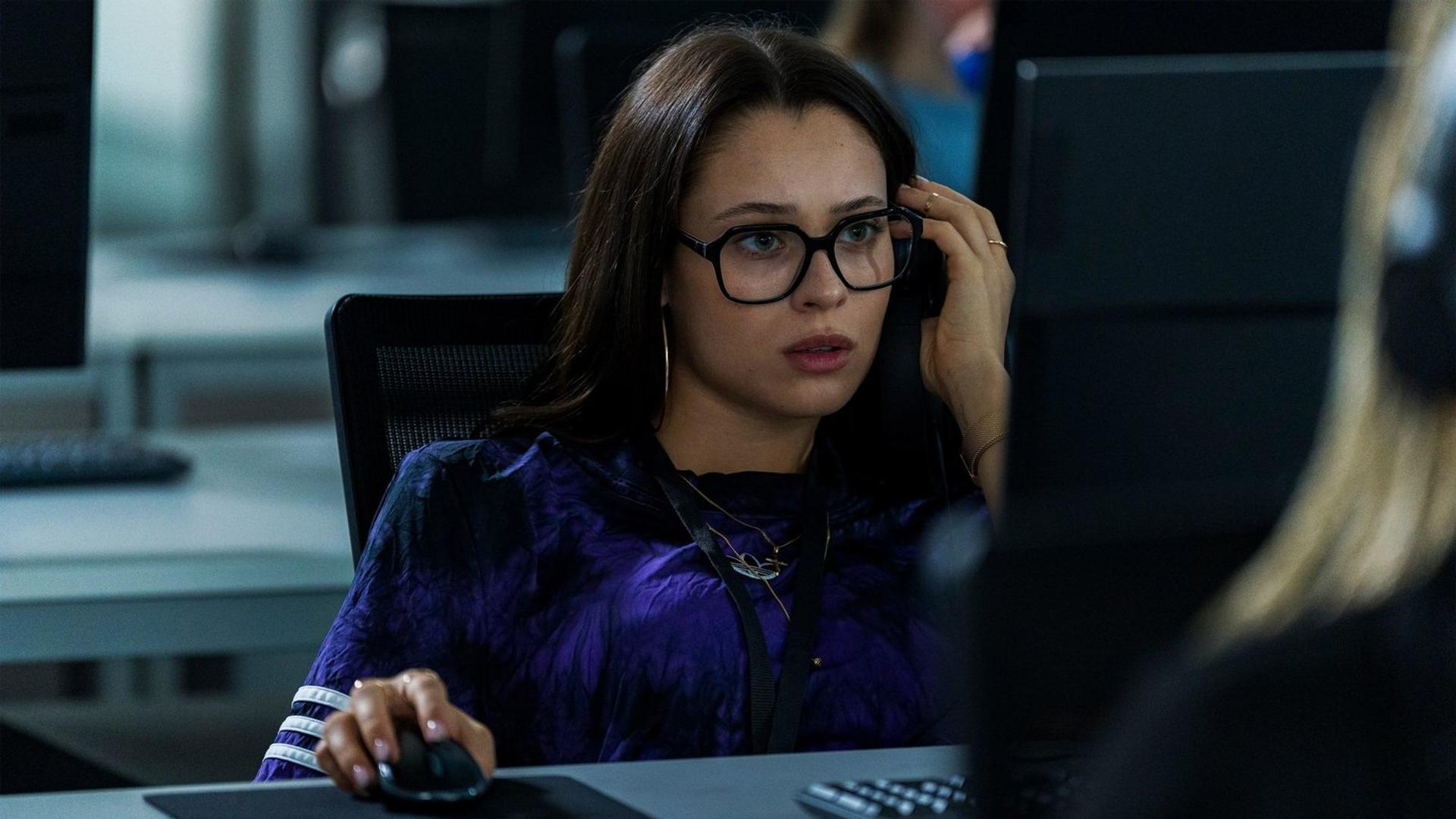 Eine dunkelhaarige Frau mit Brille sitzt konzentriert an einem Schreibtisch im Büro und bedient eine Maus.