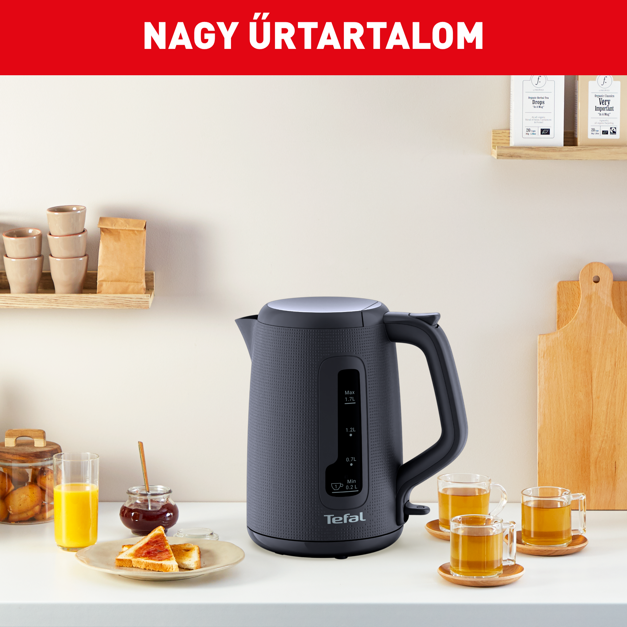 Fekete Tefal vízforraló konyhapulton pirítóssal, gyümölcslével és teáscsészékkel.