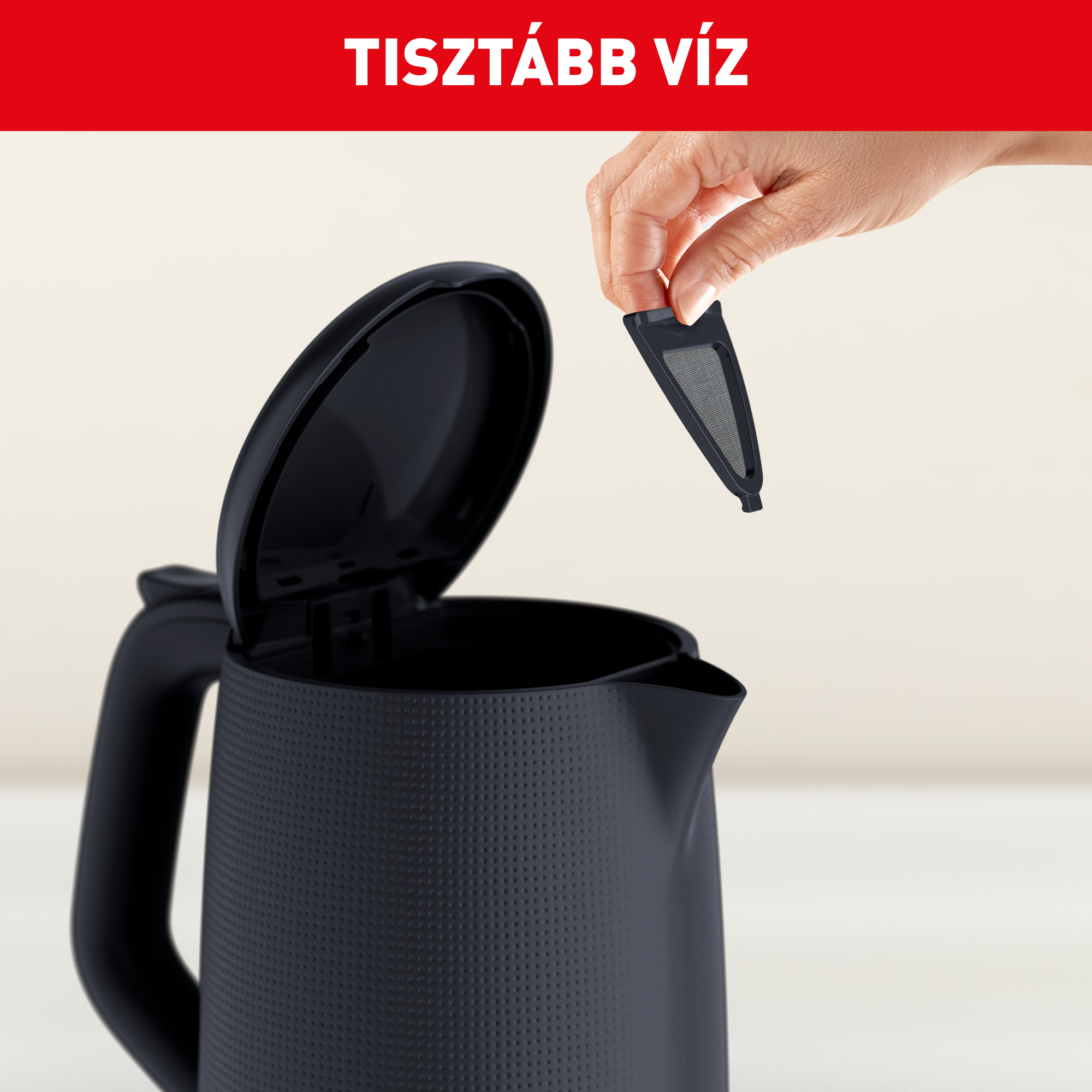 Egy kéz fekete szűrőt helyez egy nyitott fekete vízforralóba.
