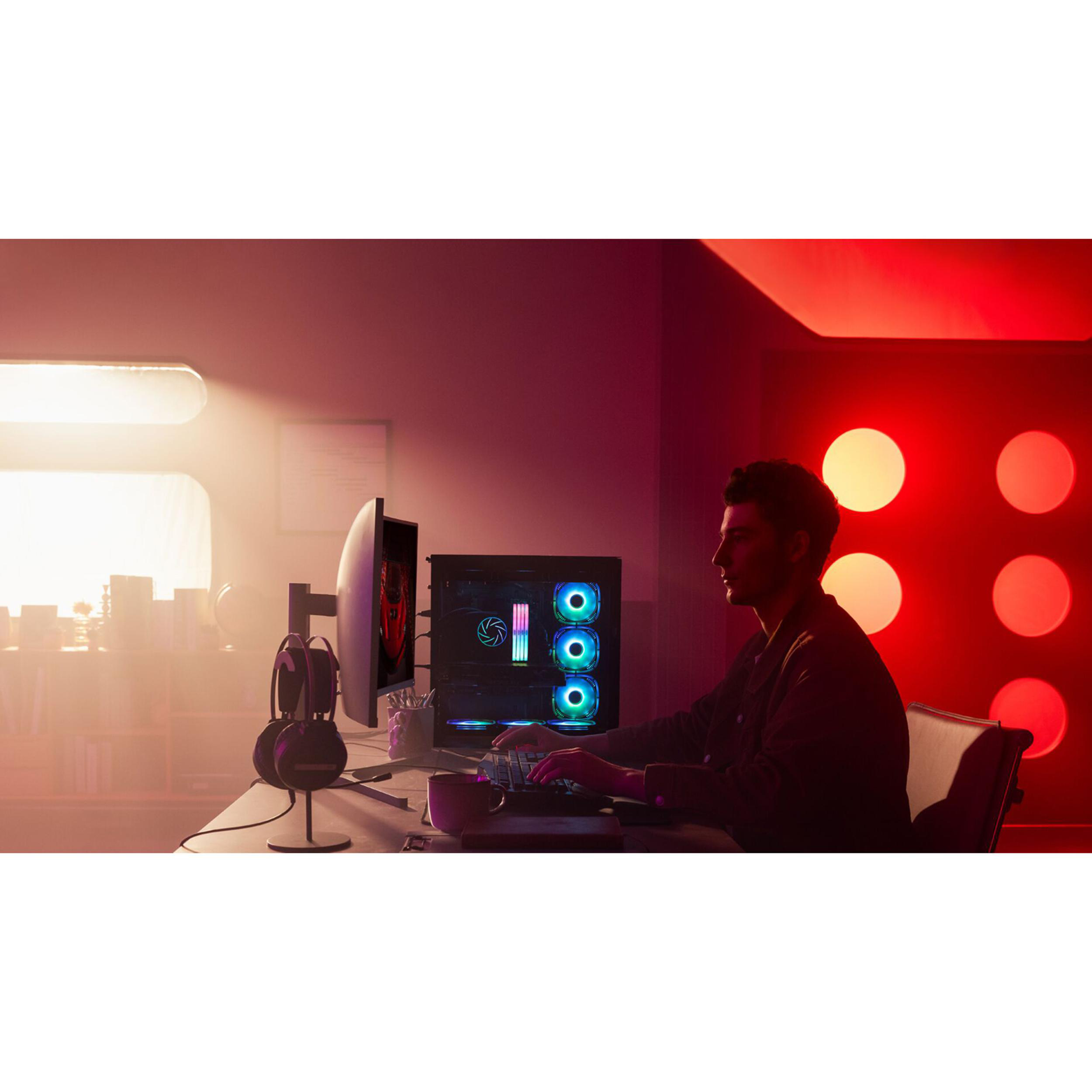 Ein Mann sitzt in rotem Licht an einem Schreibtisch vor einem Computer und tippt.