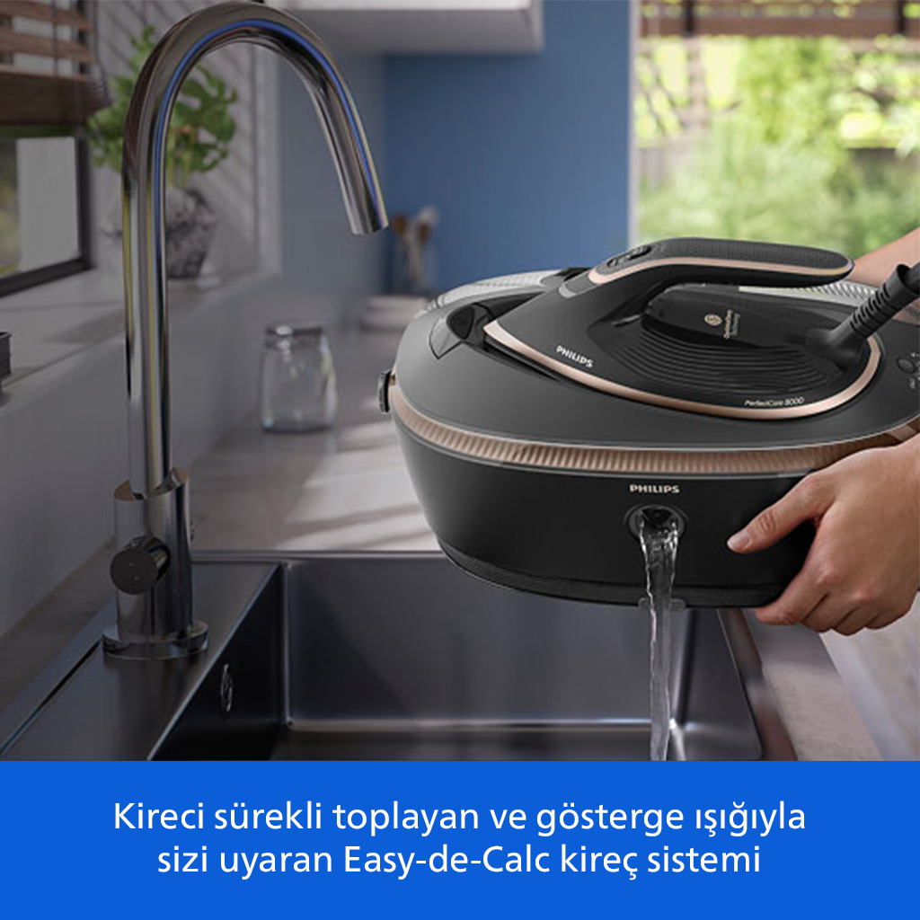 Bir kişi mutfak evyesinin üzerinde siyah Philips buhar kazanlı ütüyü suyla dolduruyor.