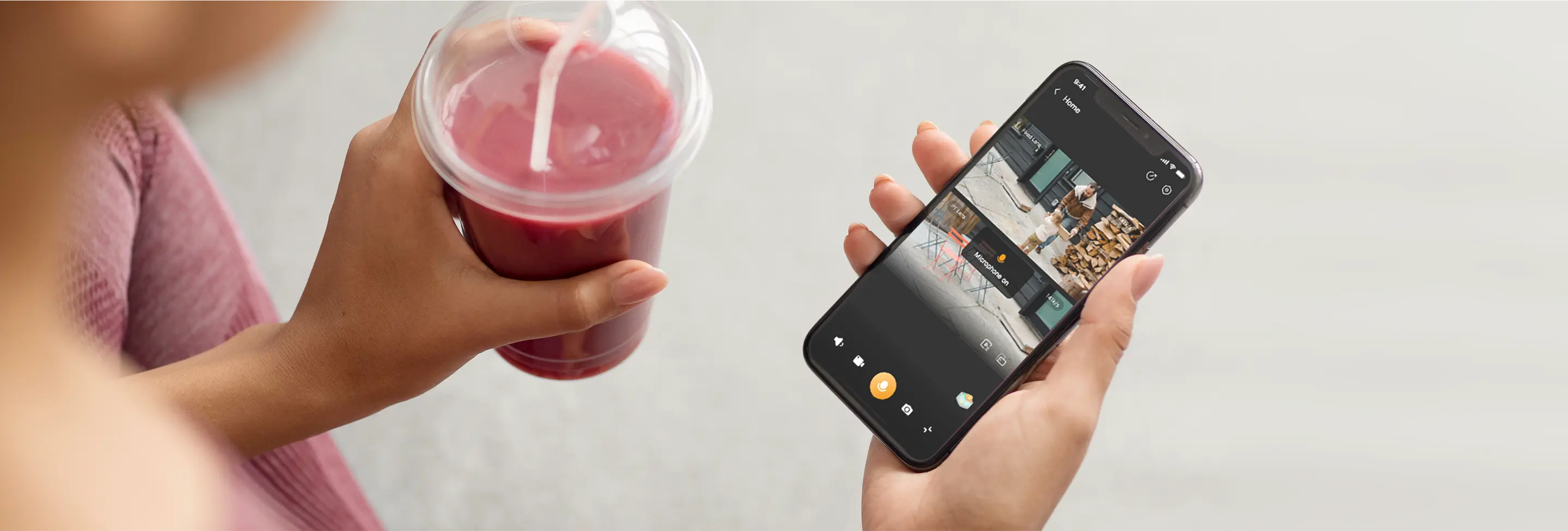 Egy személy rózsaszín smoothie-t tart az egyik kezében, és egy biztonsági kamerás okostelefont a másikban.