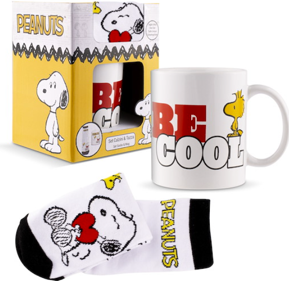 Peanuts Geschenkset mit weißer Tasse mit Aufschrift Be Cool und Snoopy-Socken vor gelber Verpackung.