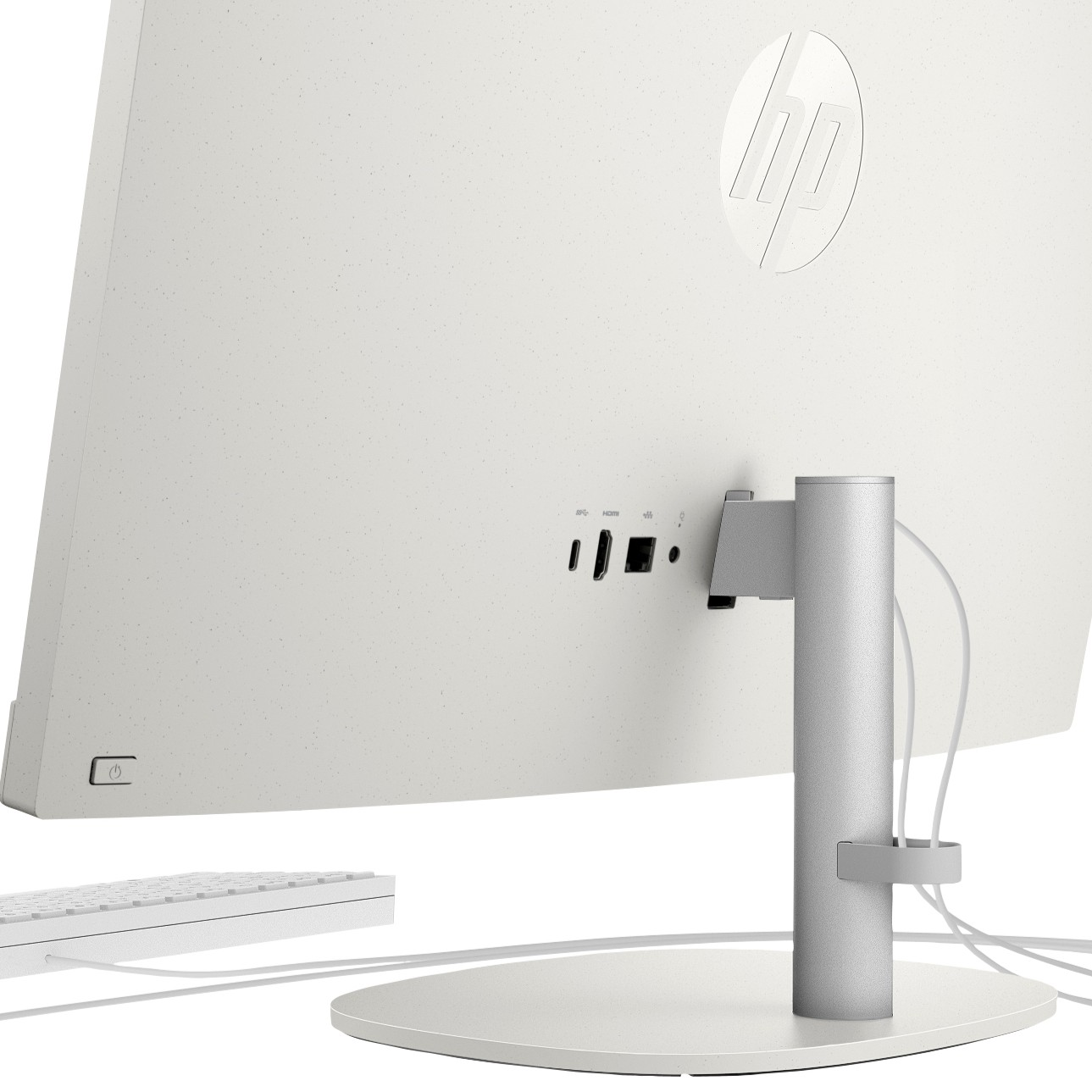 Vista trasera de una computadora todo en uno HP blanca en una mesa blanca, con cables y soporte.