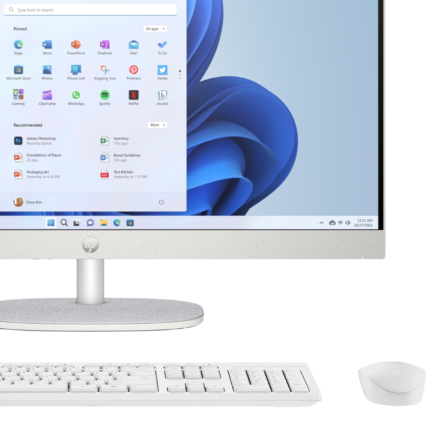 Una computadora todo en uno HP blanca muestra el menú de inicio abierto de Windows 11 con teclado y mouse blancos.