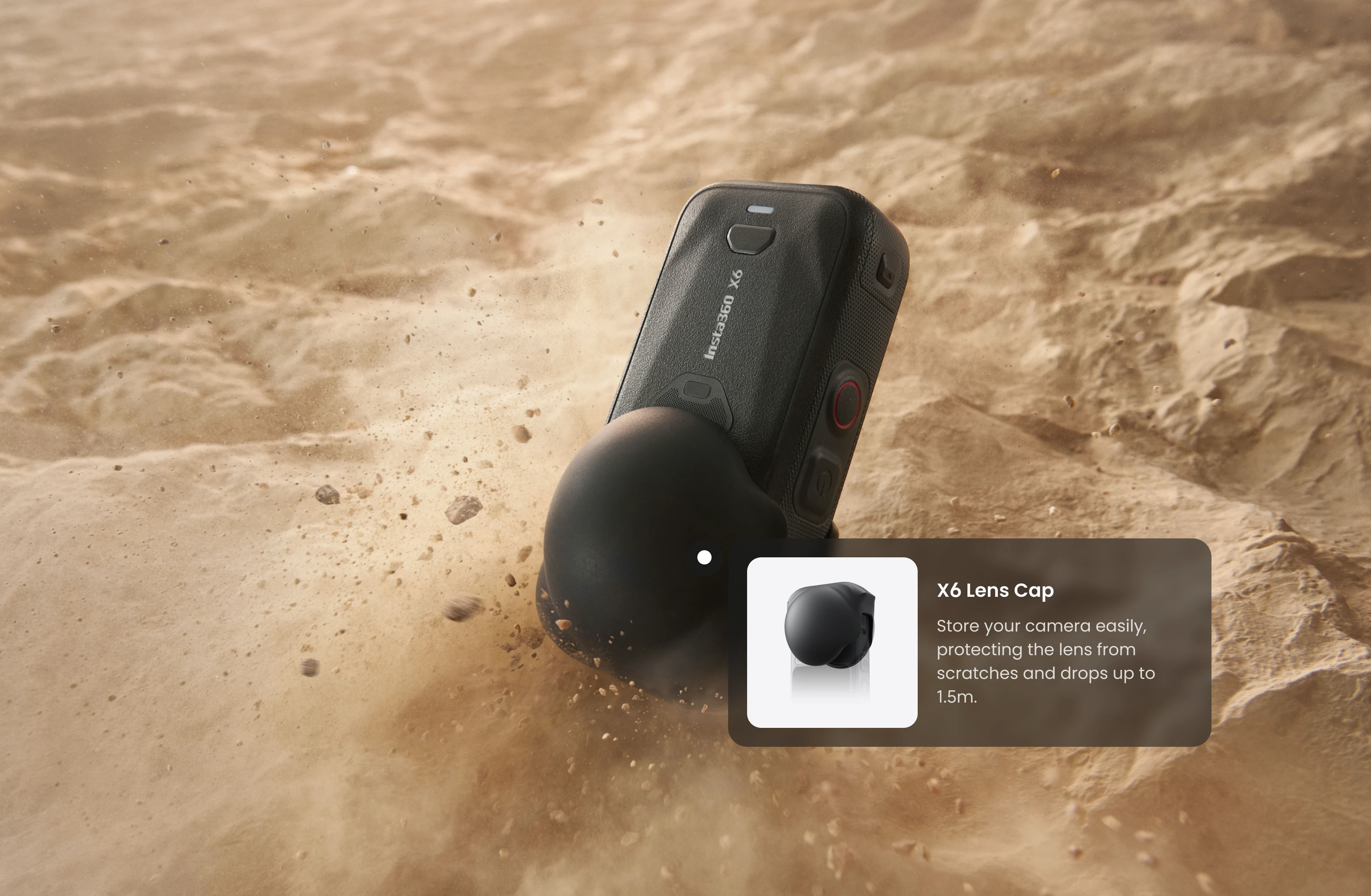 Una fotocamera nera Insta360 X6 con copriobiettivo nella sabbia del deserto con polvere.
