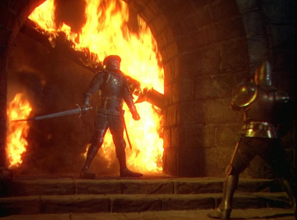 Ein Ritter in Rüstung hält ein Schwert vor einem großen Torbogen, der in hellen orangefarbenen Flammen steht.