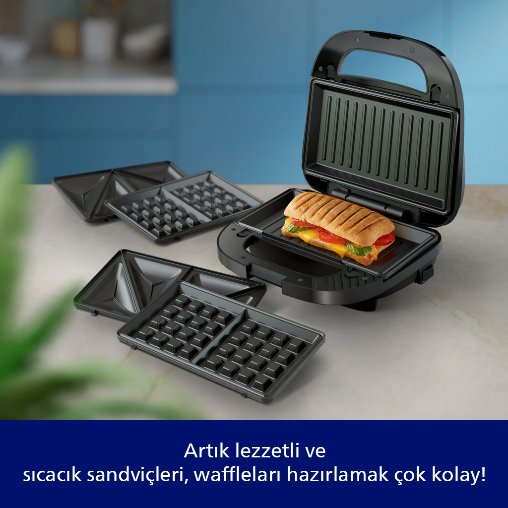 Mutfak tezgahında waffle plakaları ve sıcak bir sandviç bulunan siyah sandviç makinesi.