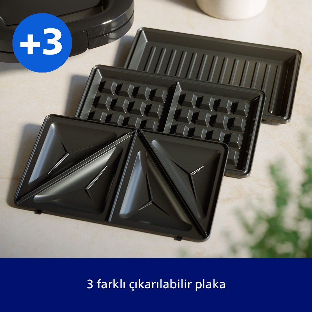 Bir tost makinesi için üç farklı çıkarılabilir plaka açık renkli bir yüzeyde duruyor.