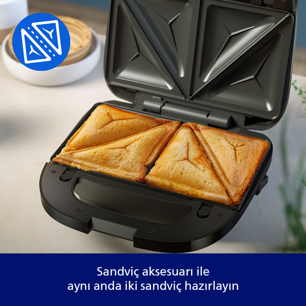 Masa üzerindeki siyah tost makinesi dört adet altınımsı kahverengi üçgen tost pişiriyor.