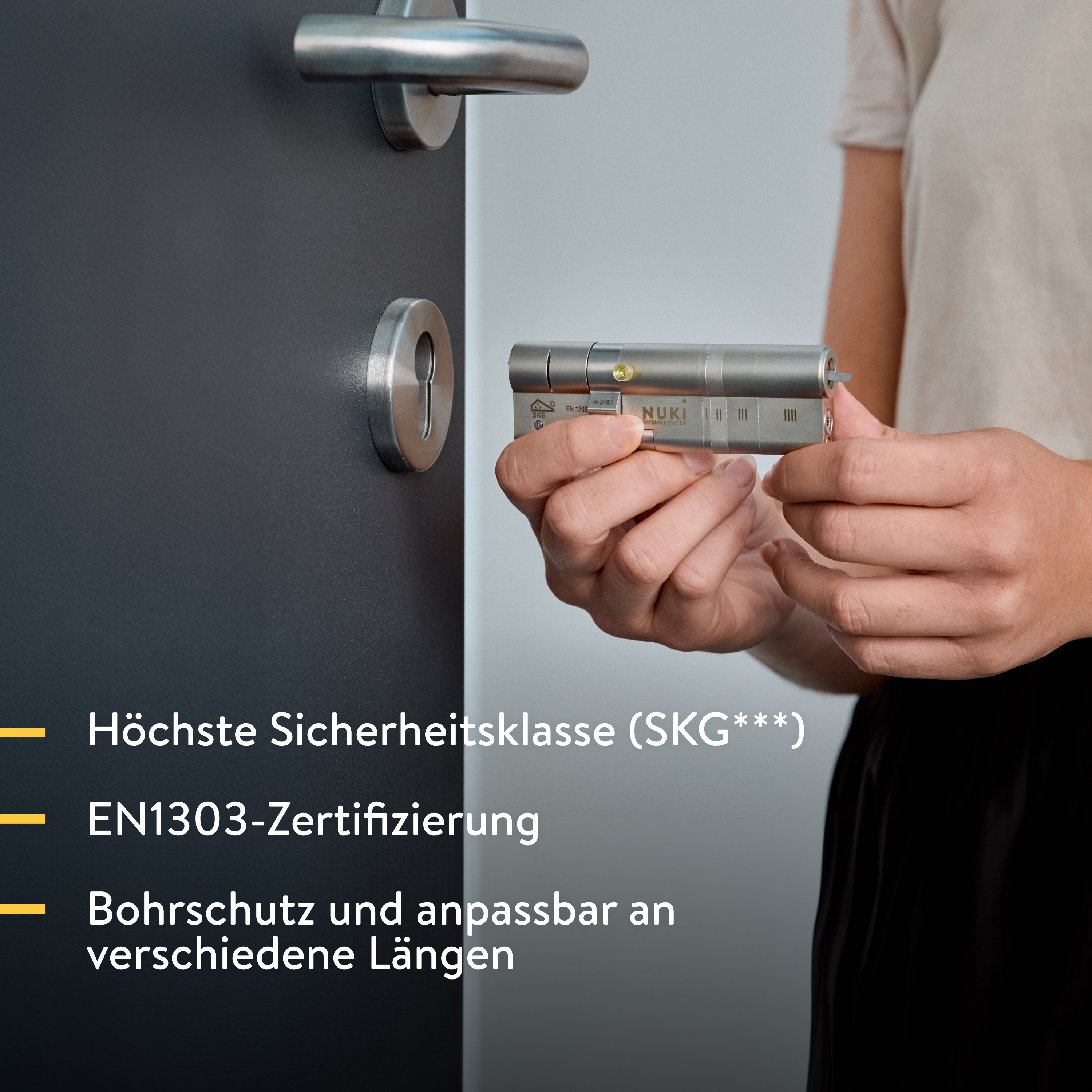 Person hält ein Nuki Smart Lock Zylinderschloss neben einer dunklen Tür.