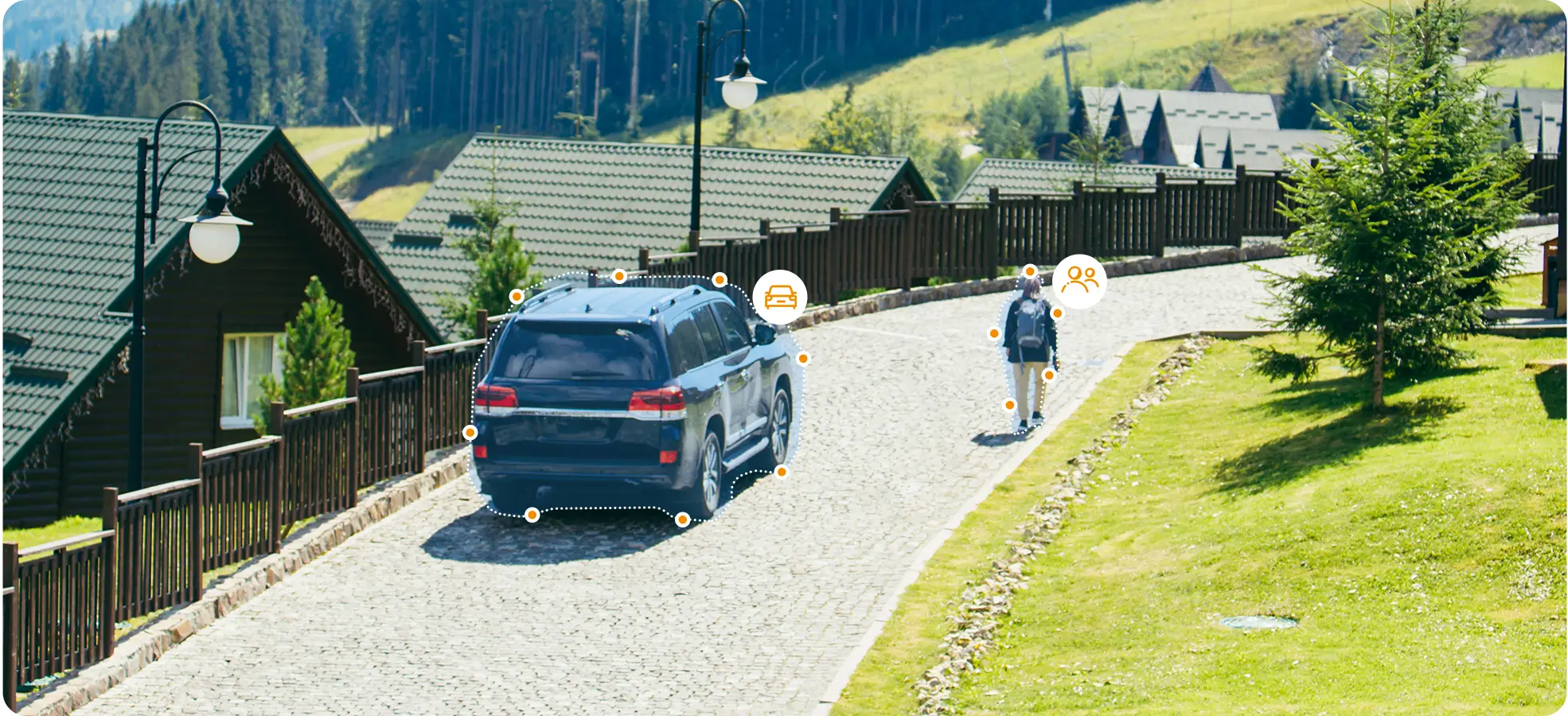 Egy sötét terepjáró parkol a macskaköves utcán faházak mellett, egy ember sétál.