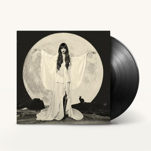 Eine Frau in einem weißen Kleid steht vor einem großen Vollmond, neben dem Albumcover liegt eine Schallplatte.