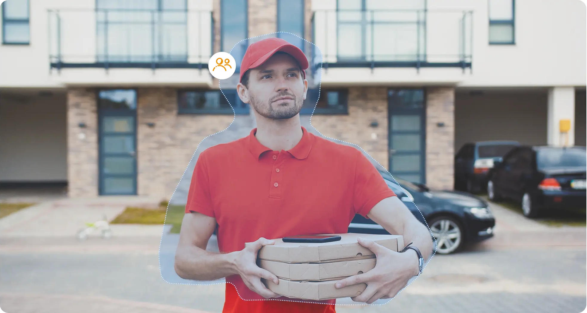 Egy piros ruhás futár pizzás dobozokat tart egy lakóépület előtt.