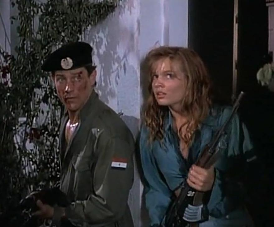 Ein Mann in Militäruniform mit Beret und eine Frau mit Gewehr stehen an einer Wand.