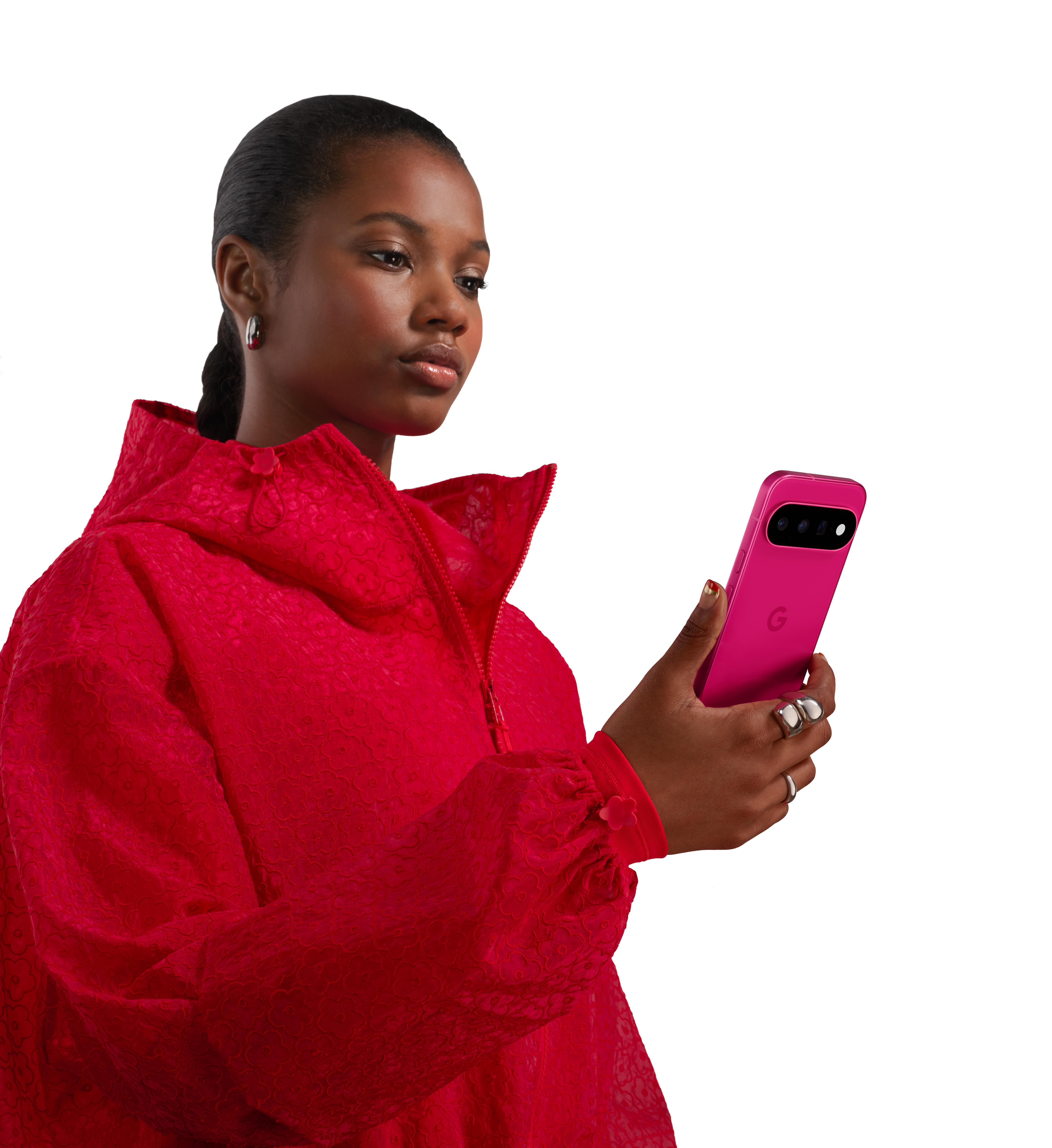 Eine junge Frau in einer roten Jacke hält ein pinkes Smartphone in der Hand.