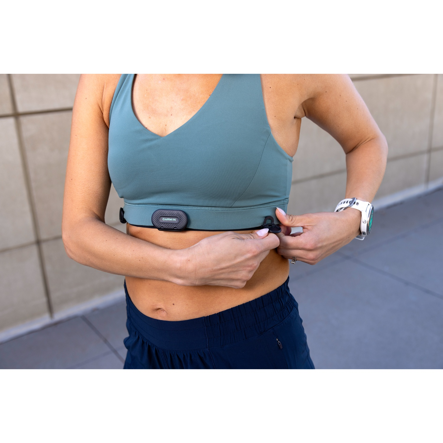 Een vrouw in sportkleding doet een Garmin hartslagmeterband om.