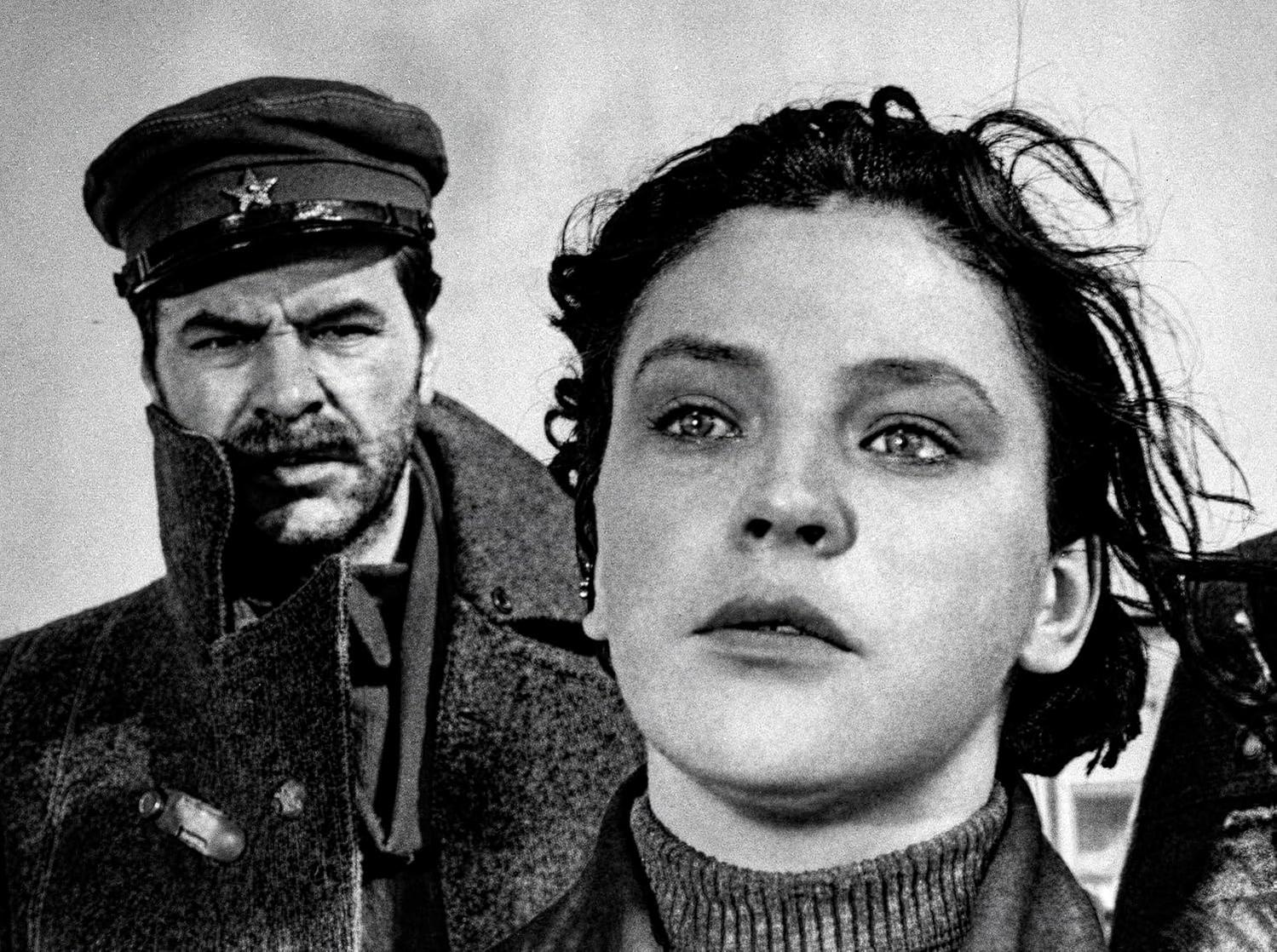 Schwarz-Weiß-Foto einer Frau im Vordergrund mit einem ernsten Mann im Hintergrund.