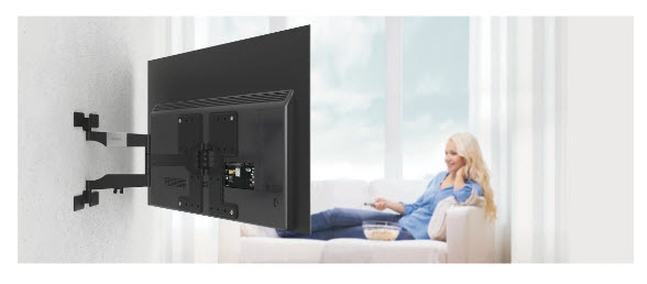 Ein Fernseher ist an einer Wandhalterung montiert, während eine Frau auf einem Sofa sitzt.