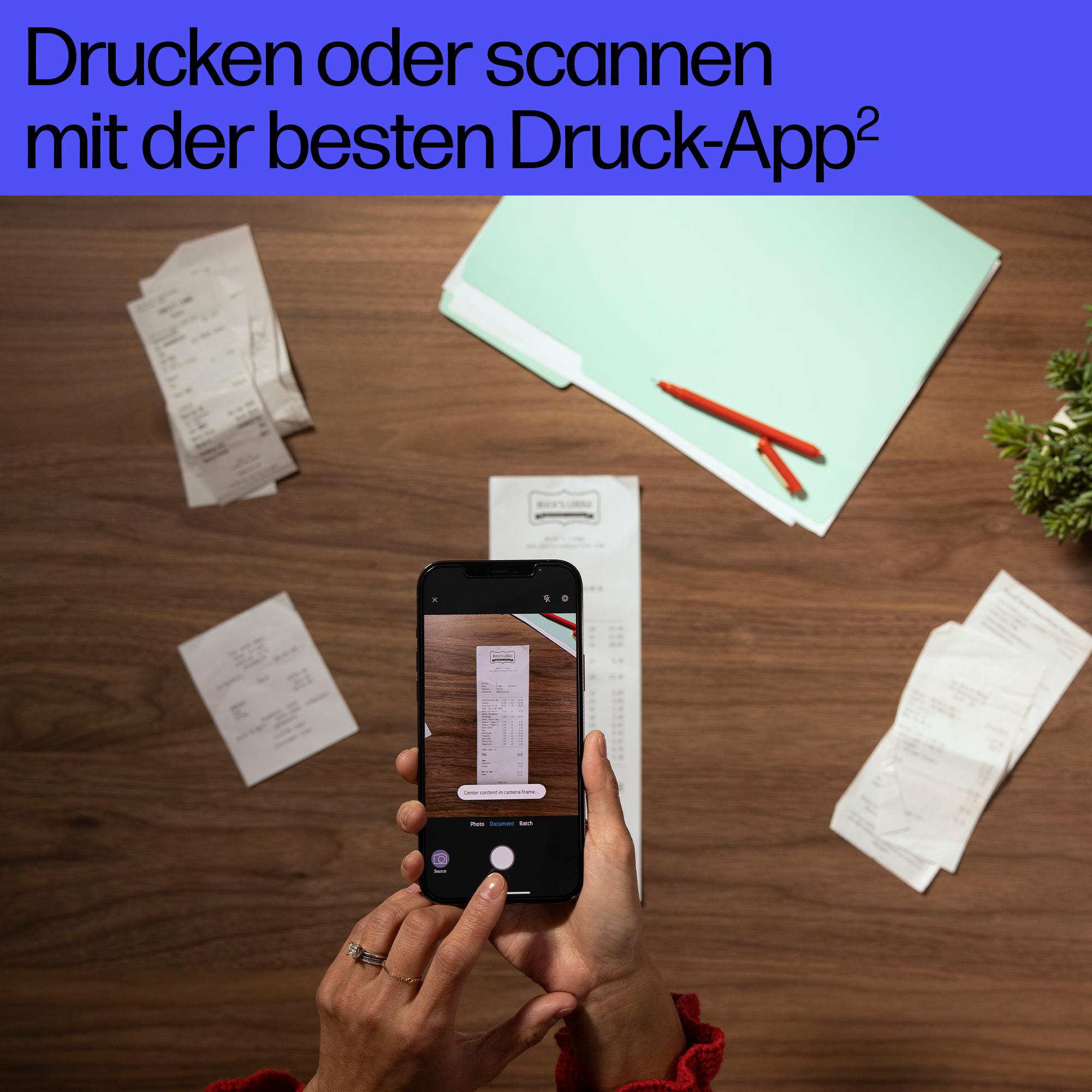 Person scannt einen Kassenbon mit einem Smartphone auf einem Holztisch mit Dokumenten.