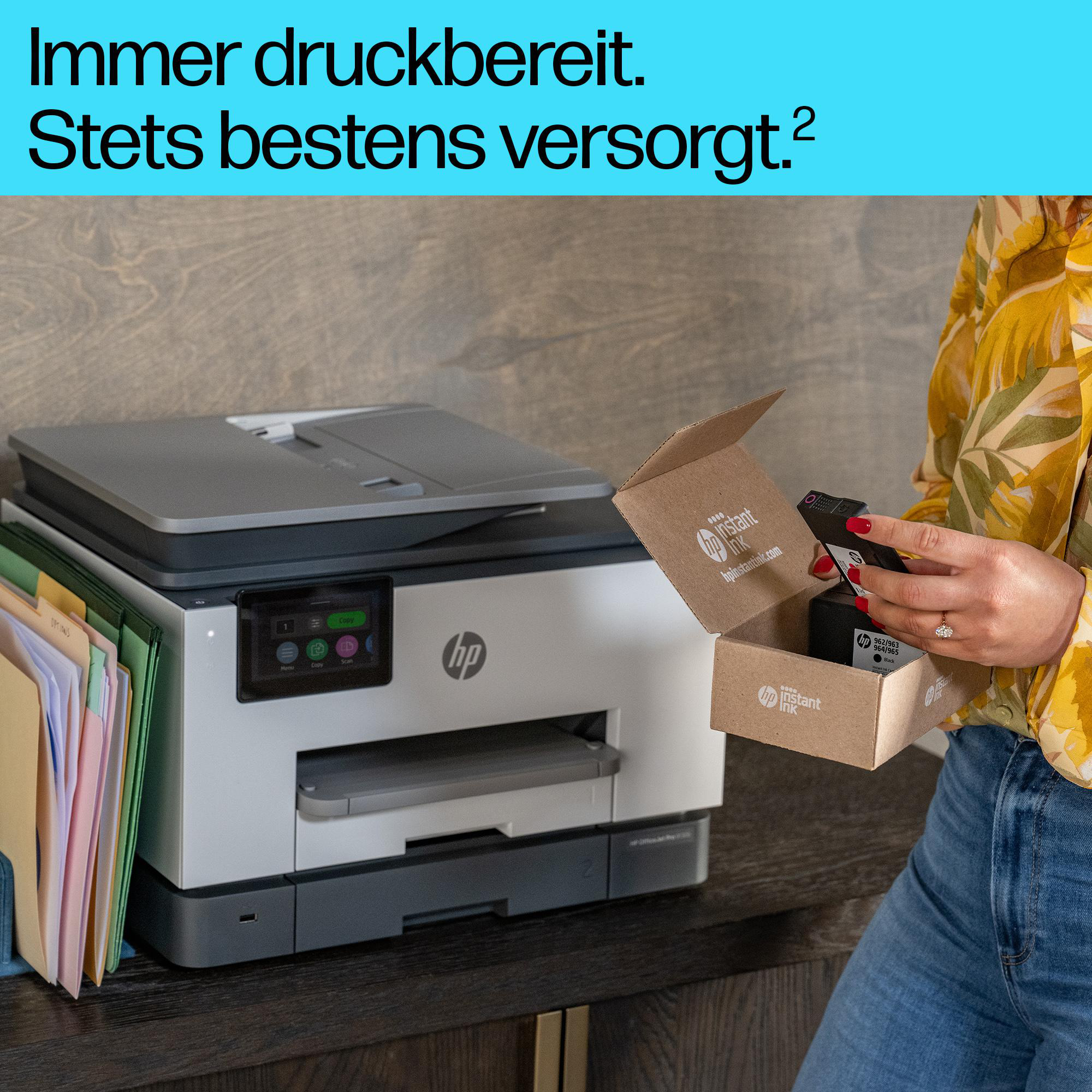 Eine Frau hält eine geöffnete HP Instant Ink Schachtel neben einem HP Drucker.