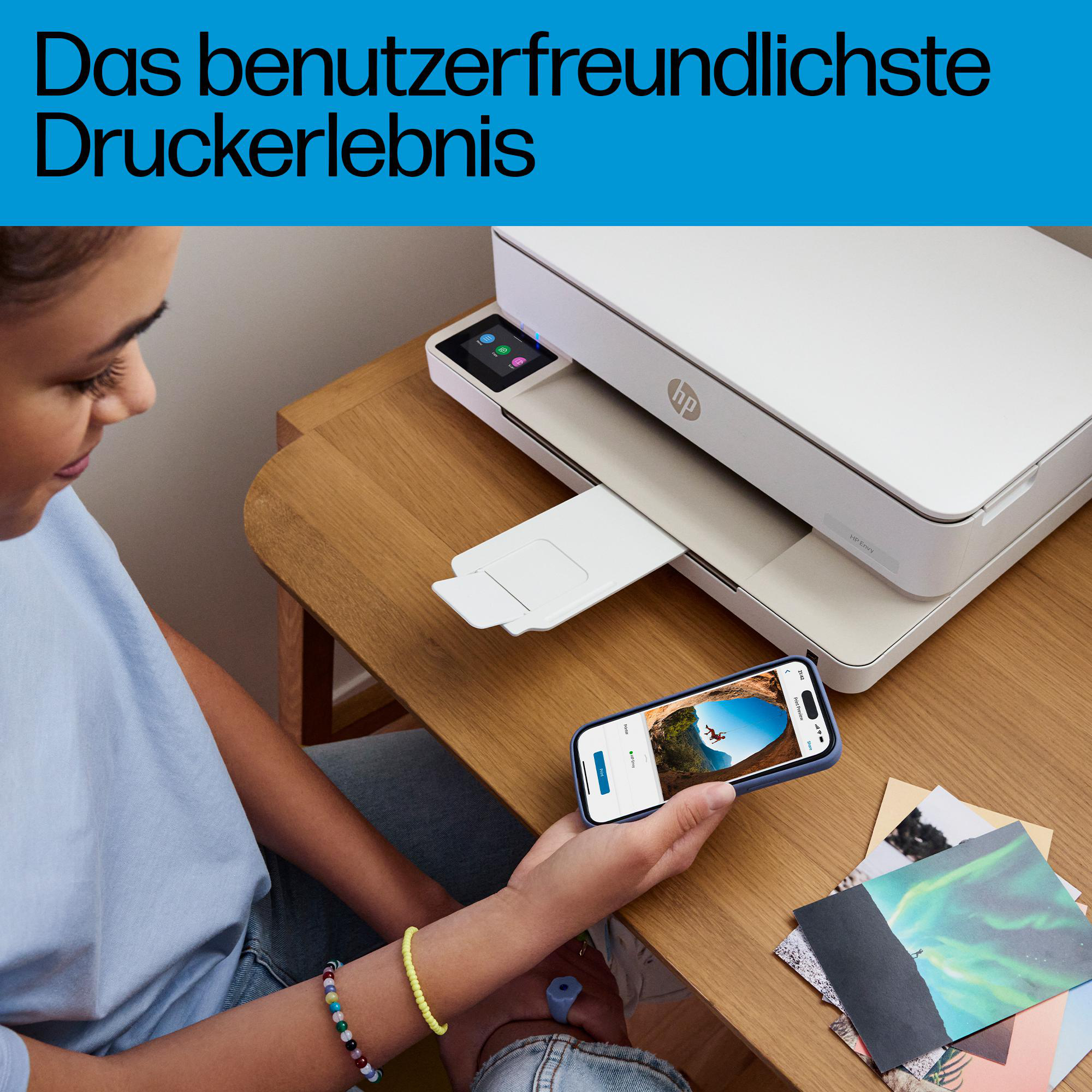Ein Mädchen druckt ein Foto von ihrem Smartphone auf einem weißen HP Drucker an einem Holztisch aus.