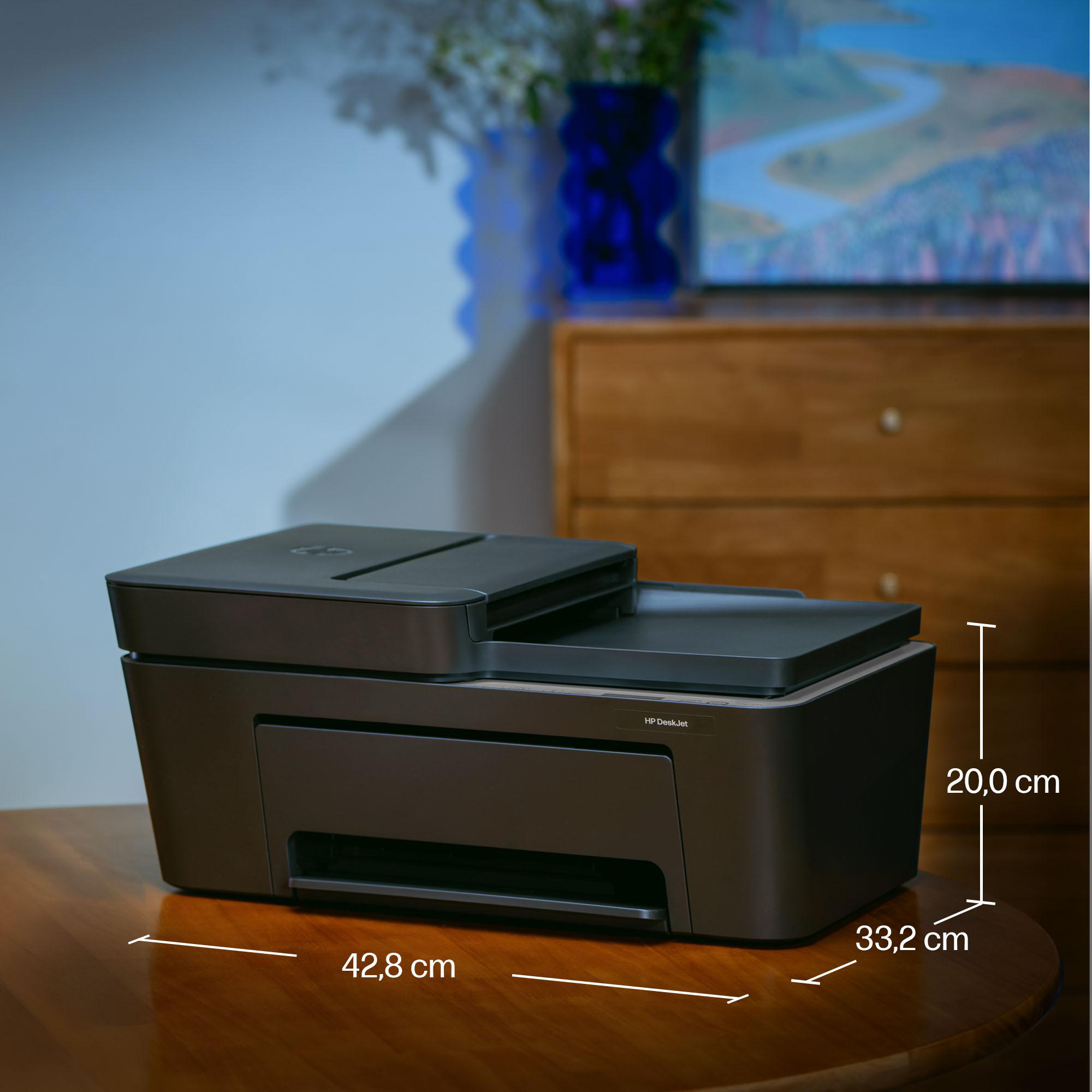 Ein grauer HP DeskJet-Drucker steht auf einem Holztisch, mit Maßangaben für Breite, Tiefe und Höhe.