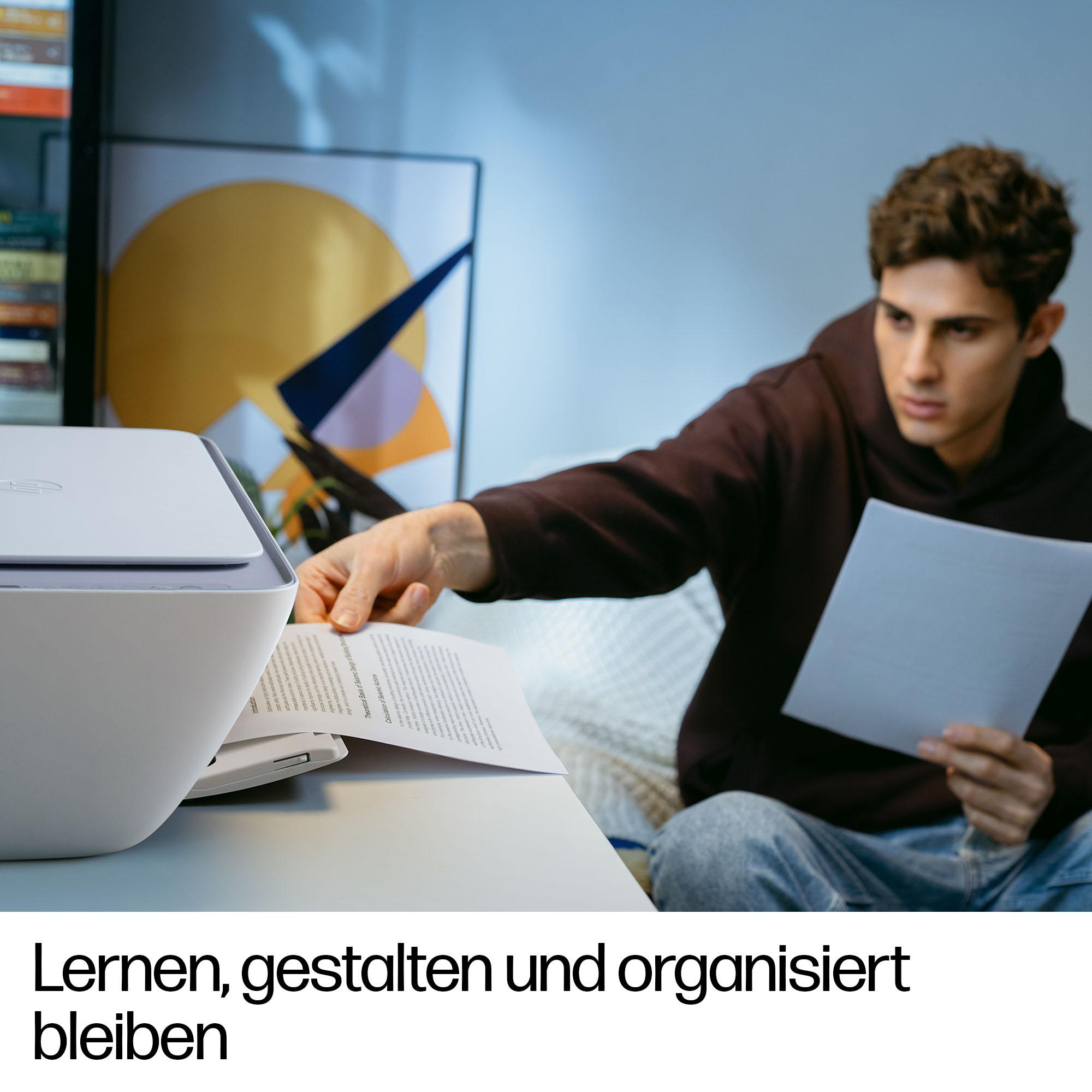 Ein junger Mann holt bedrucktes Papier aus einem weißen Drucker in einem modernen Raum mit Kunst an der Wand.