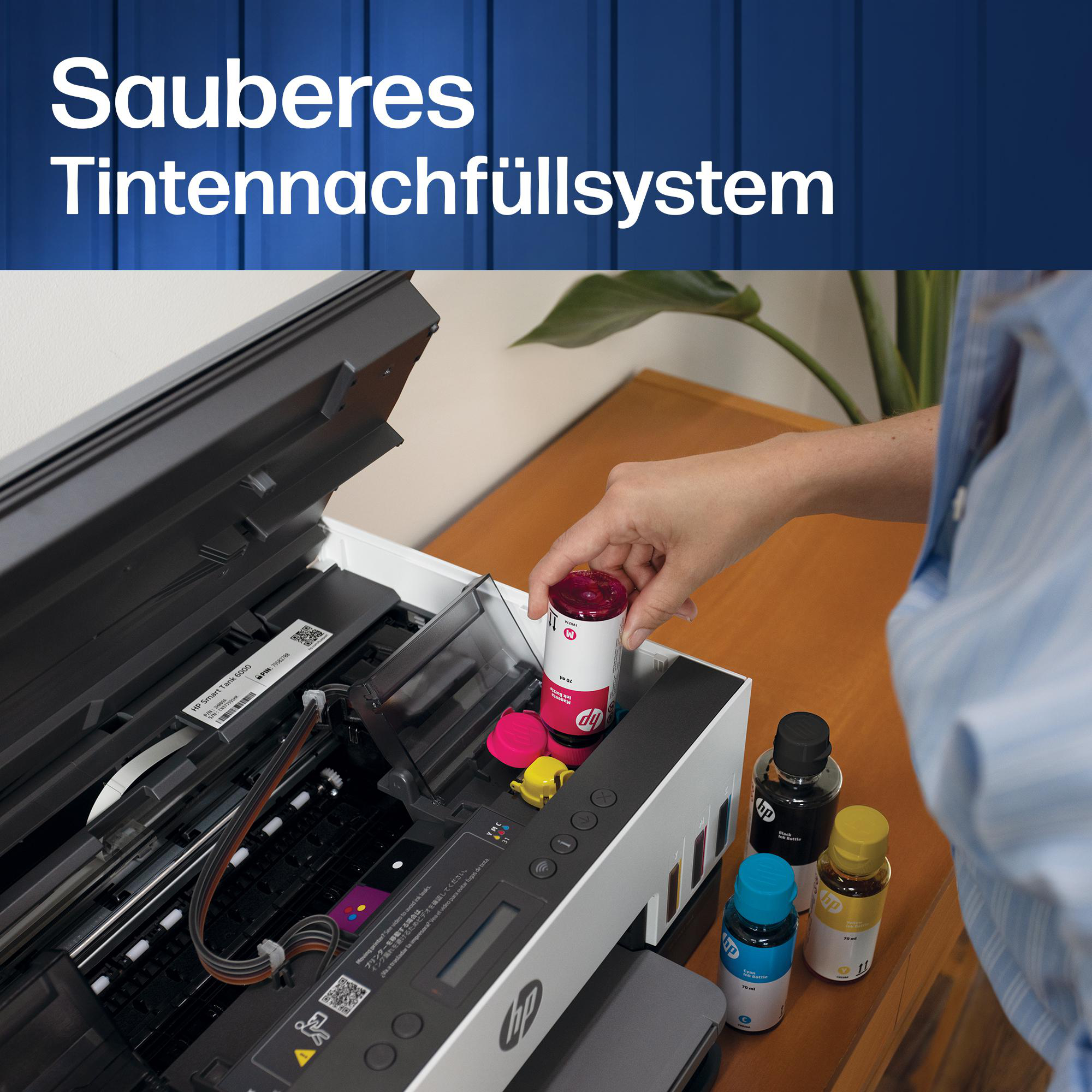 Person füllt magenta Tinte in einen HP Smart Tank Drucker. Weitere Tintenflaschen stehen auf dem Tisch.