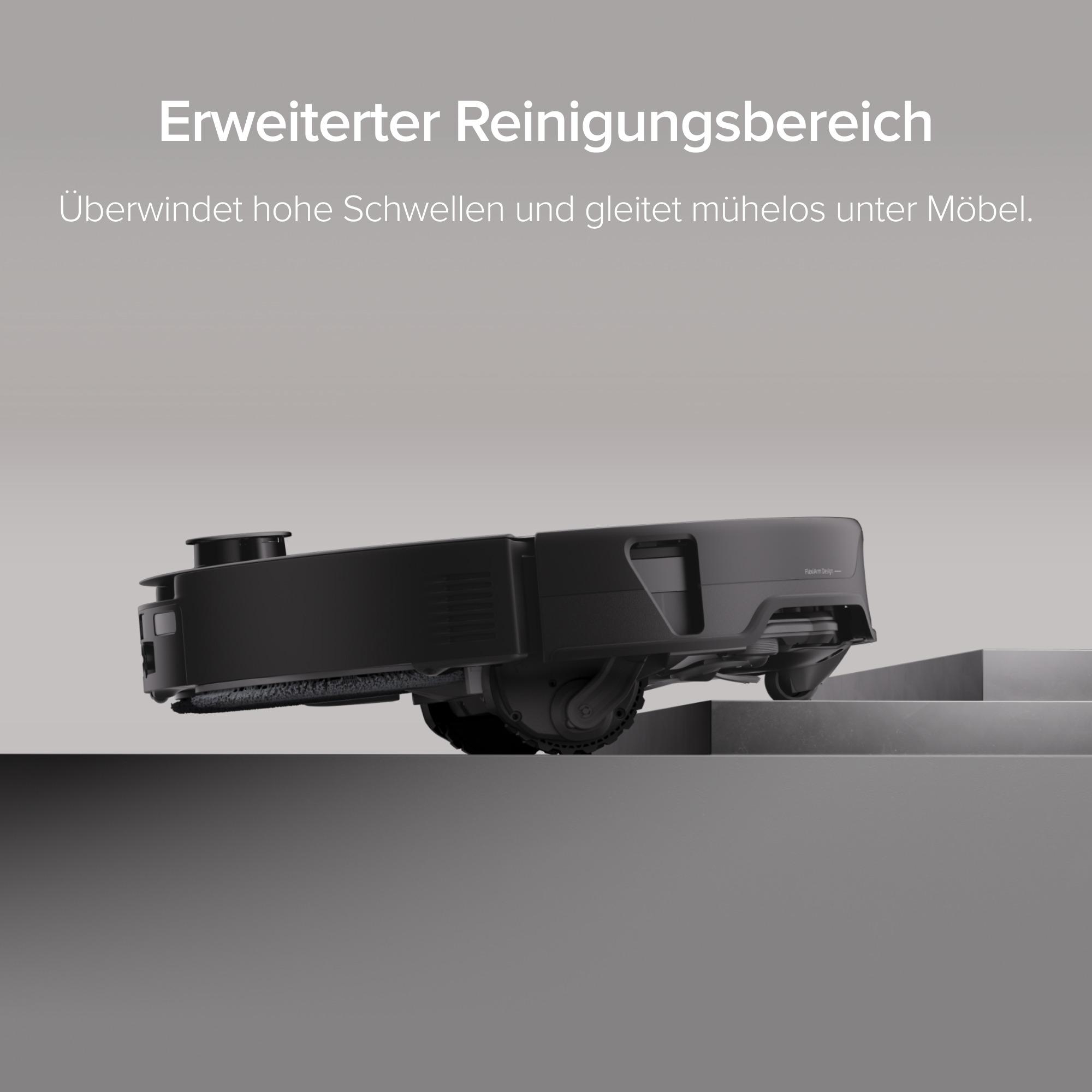 Ein schwarzer Saugroboter klettert über eine hohe Schwelle auf einer grauen Oberfläche.