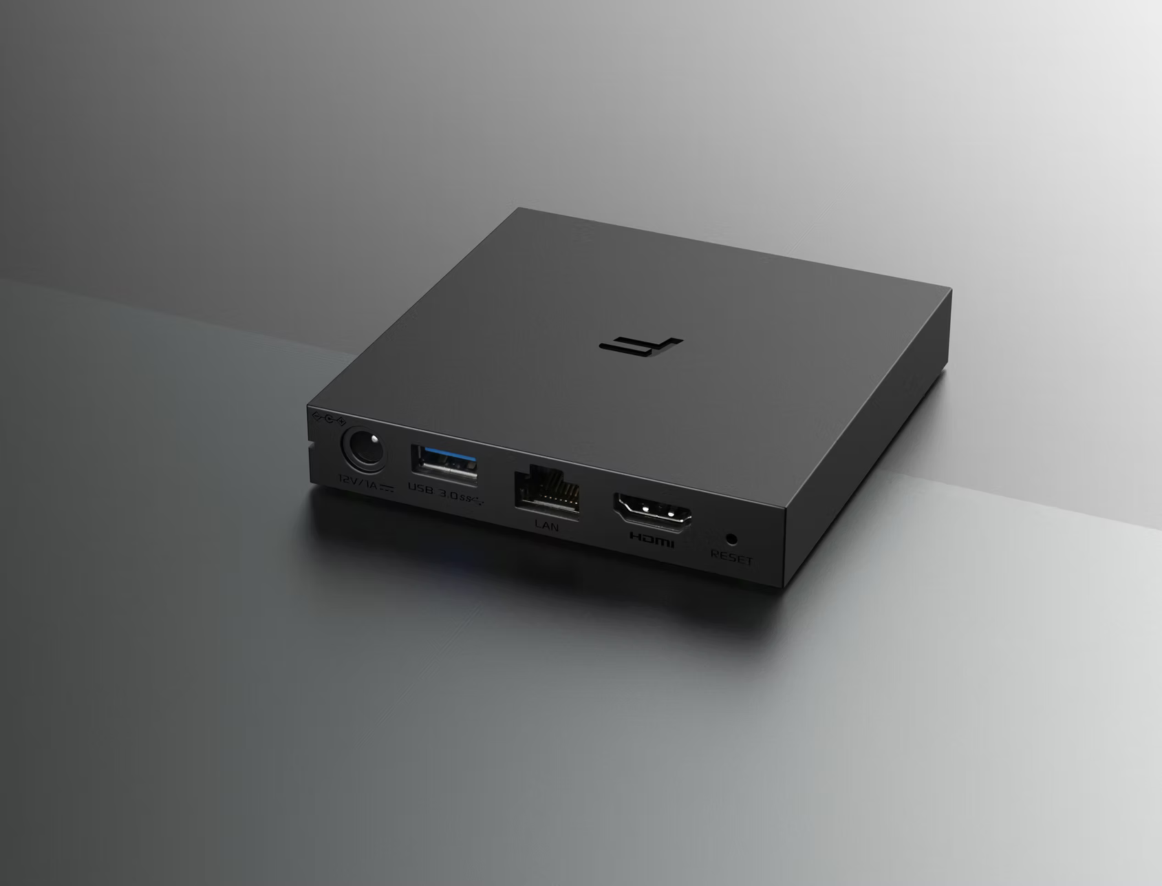 Un media box grigio con porte USB, LAN e HDMI su una superficie grigia.