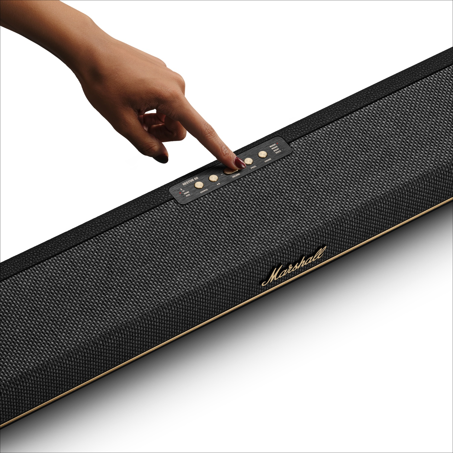 Une main appuie sur les boutons dorés d'une barre de son Marshall noire avec du tissu gris.