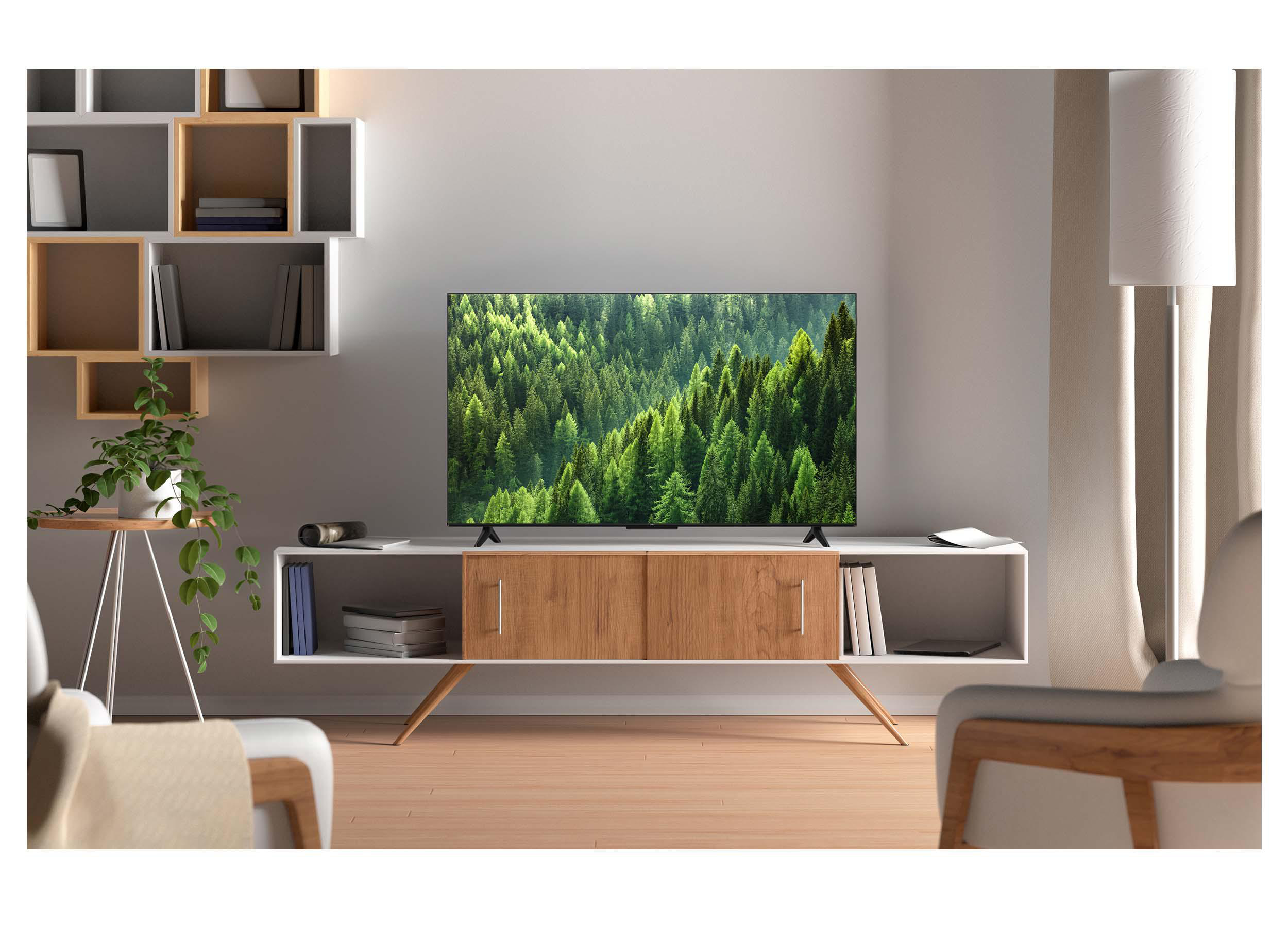 Ein weißer und hölzerner TV-Ständer mit einem Wald-Fernseher, Regalen, Pflanzen und Sesseln in einem hellen Raum.
