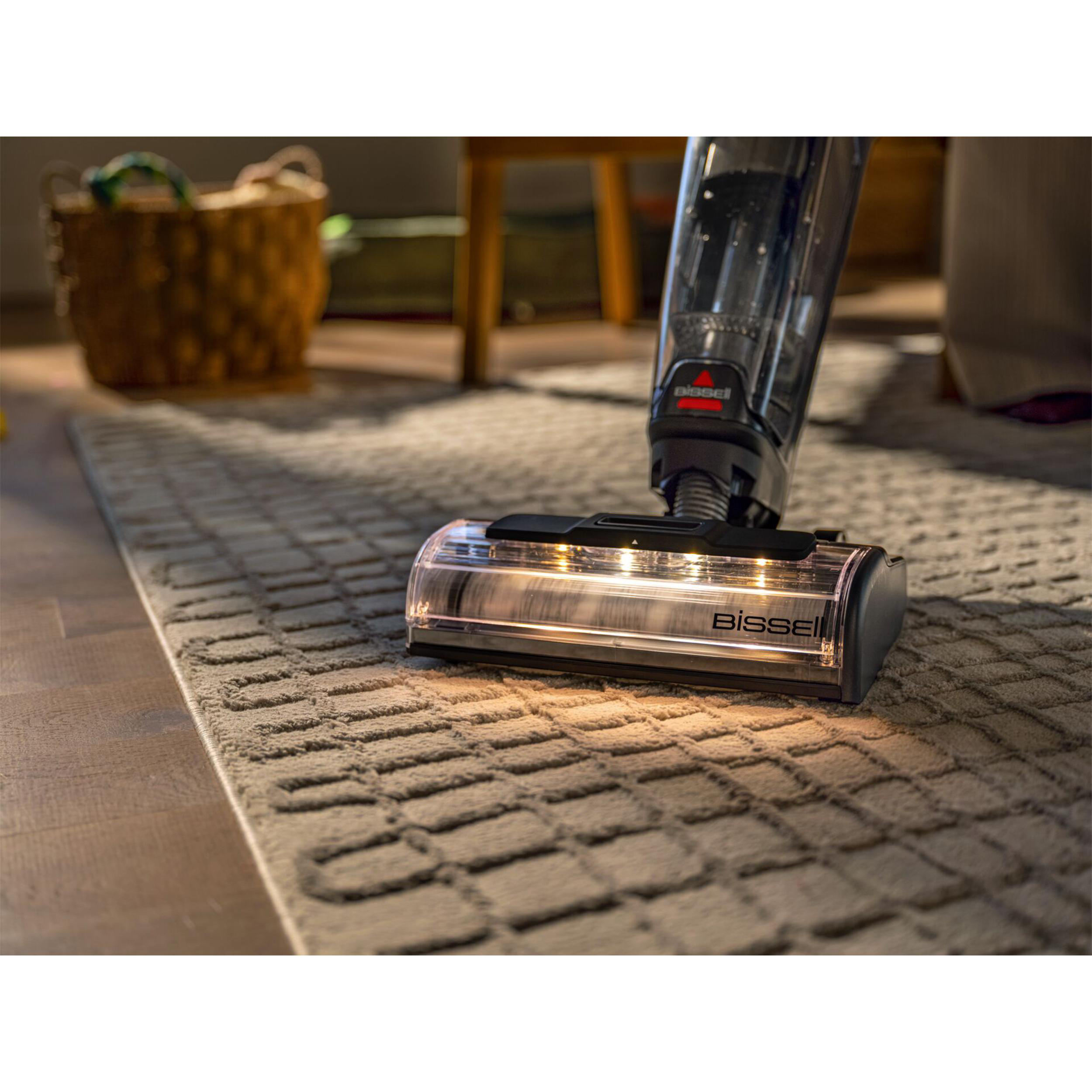 Ein Bissell-Staubsauger mit beleuchteter Bürstenrolle reinigt einen strukturierten Teppich in einem Raum.