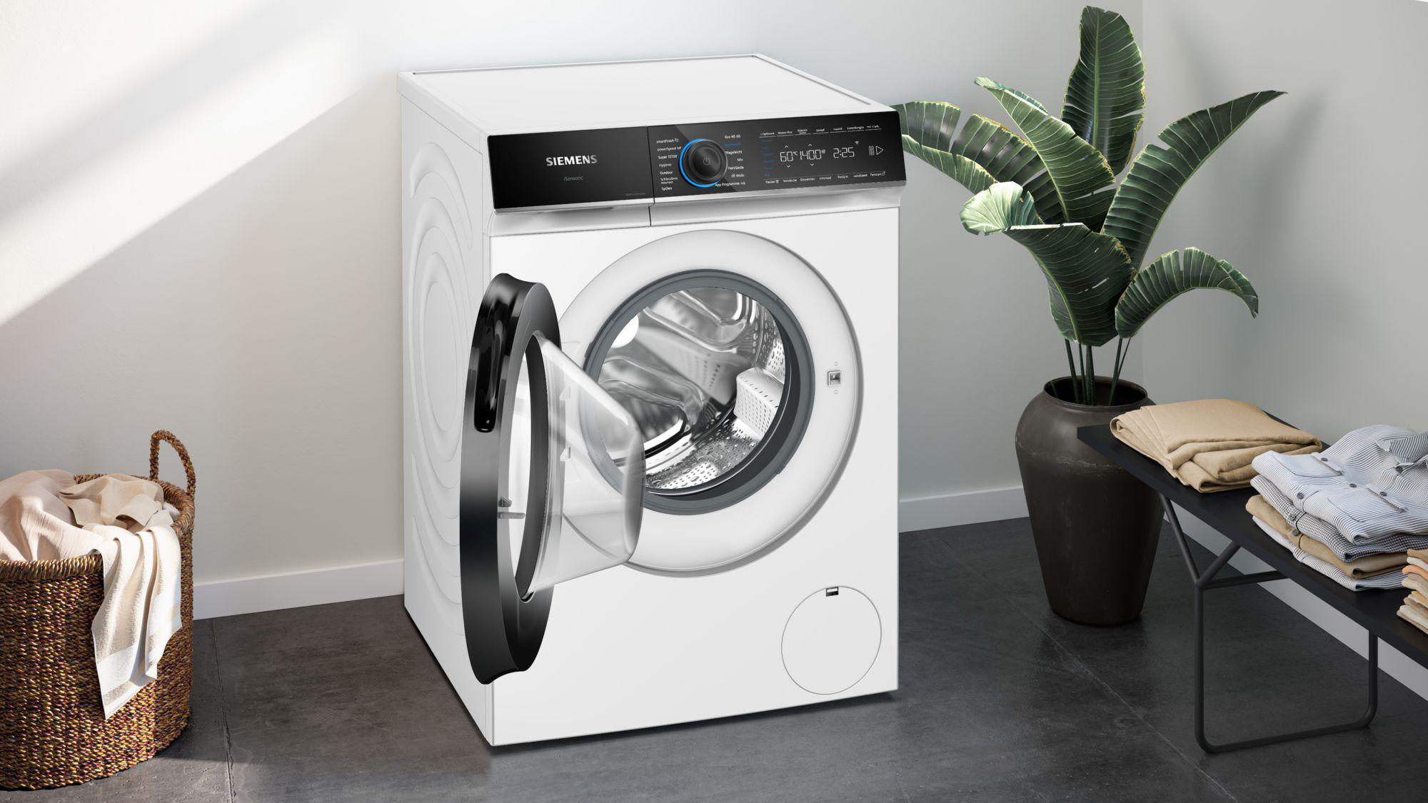 Eine weiße Siemens-Waschmaschine mit offener Tür steht in einem modernen Raum mit einer Pflanze.