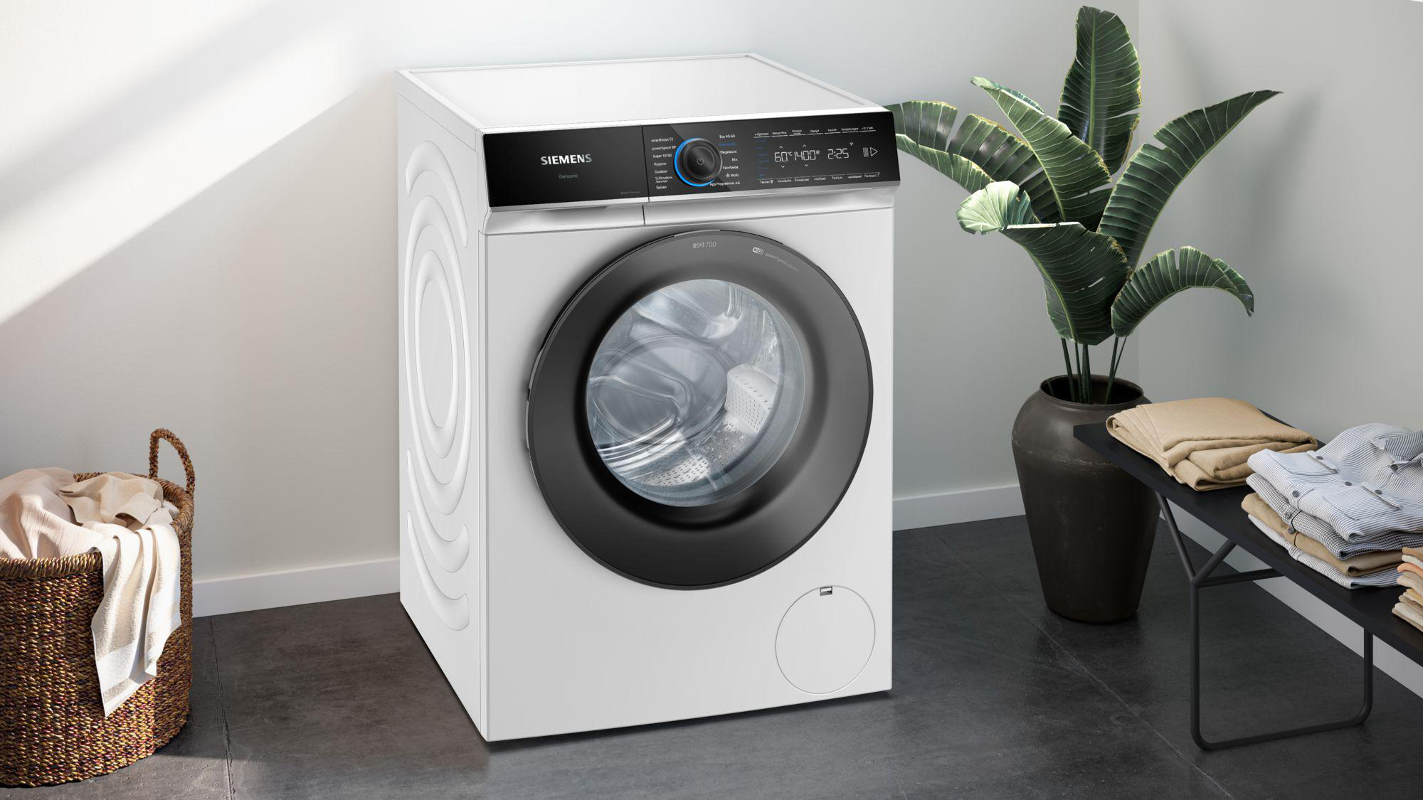 Eine weiße Siemens Waschmaschine steht in einem modernen Raum mit einem Korb und einer Bank mit Kleidung.